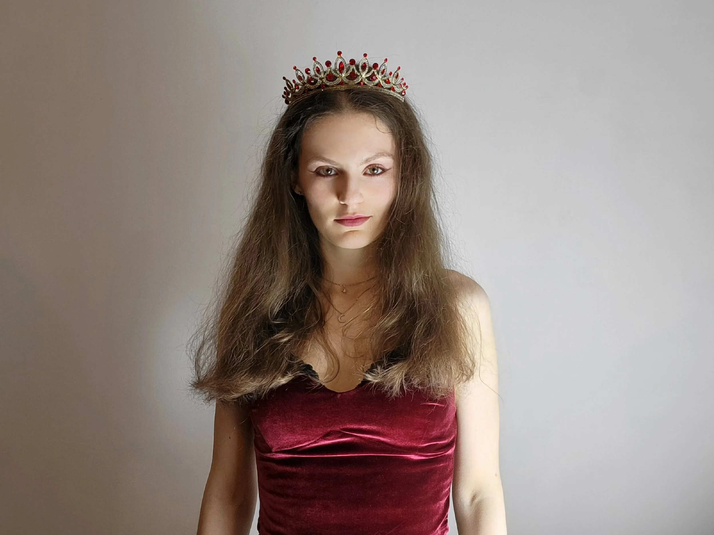 singer Patty Hago wearing a crown and a red top, hair flowing freely around her shoulders, against a neutral background.