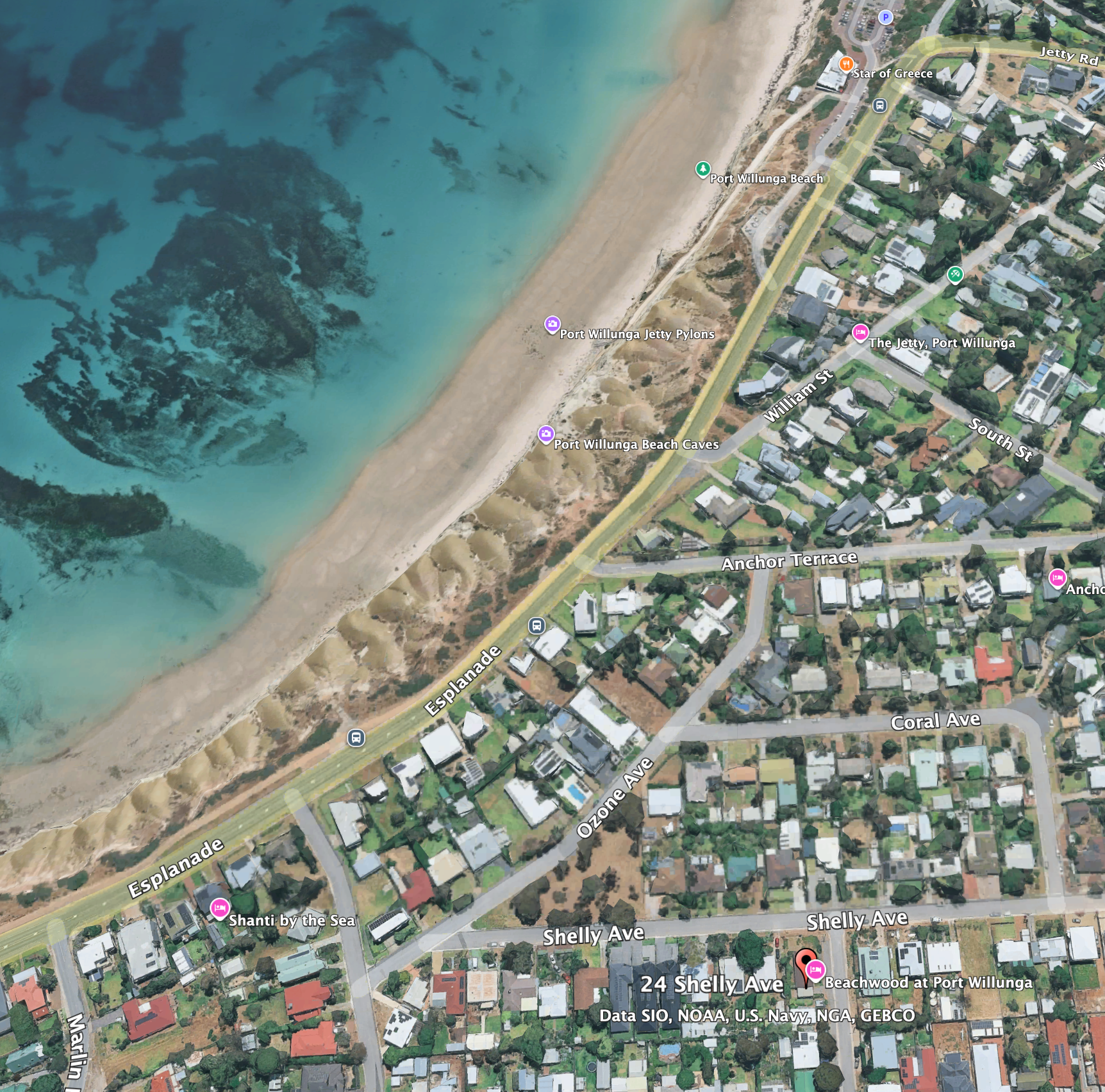 Satellite view of Port Willunga Beach and surrounding residential area, showing streets, houses, and water with visible reef structures off the coast.