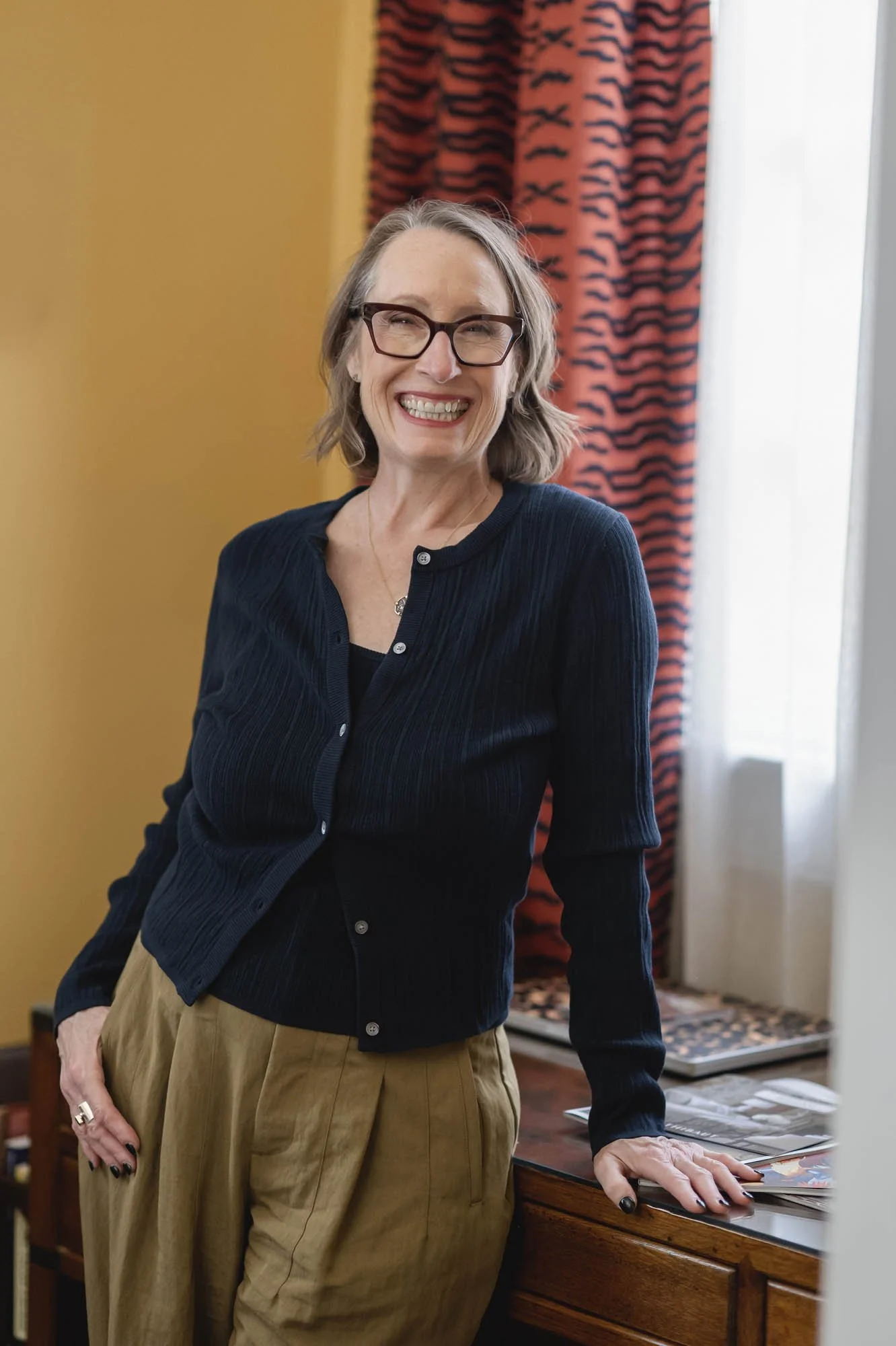 Editorial portrait of the Lamplit Atelier founder against a mustard wall