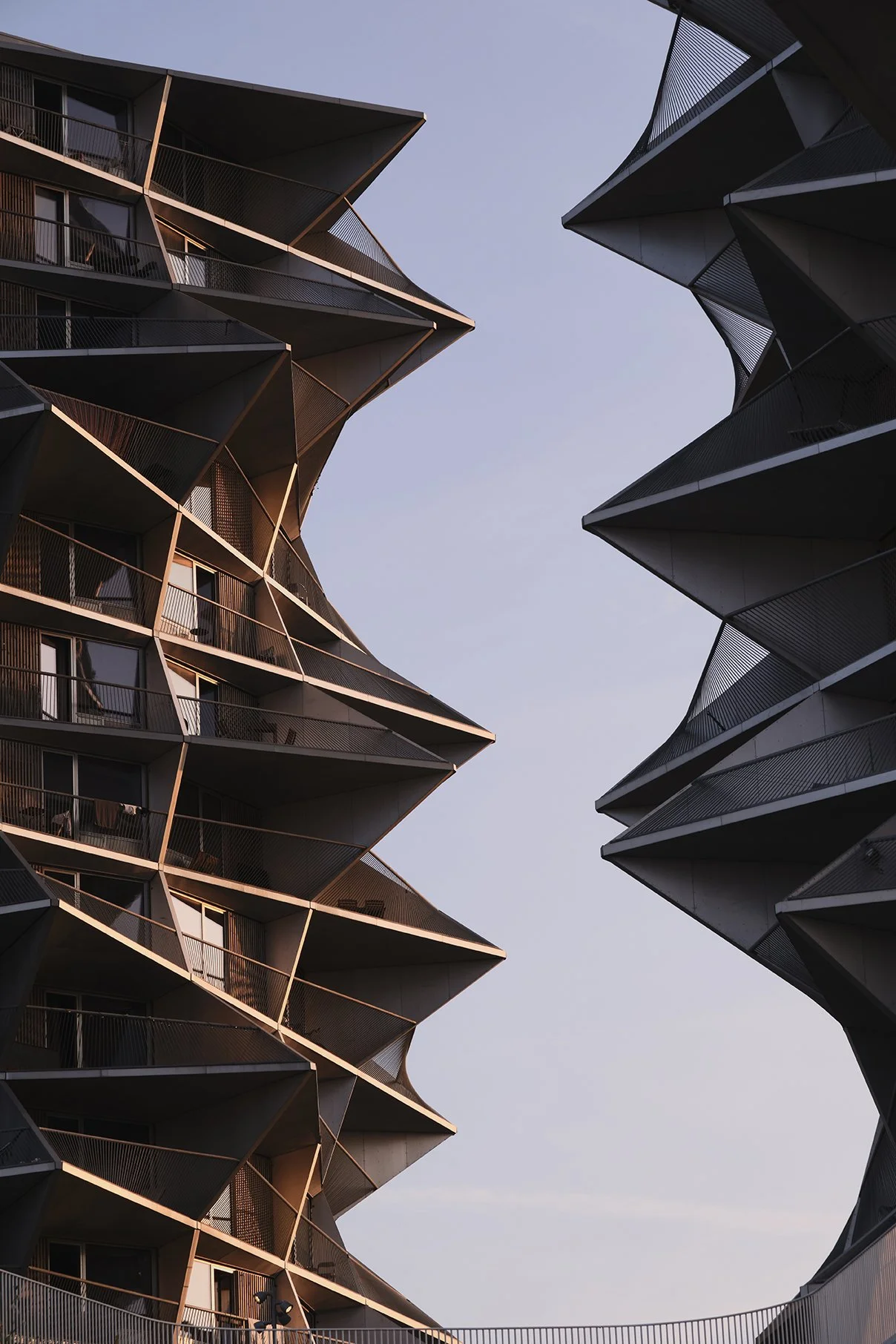 To moderne boligbygninger set udefra mod himlen med unikke geometriske facader og værn