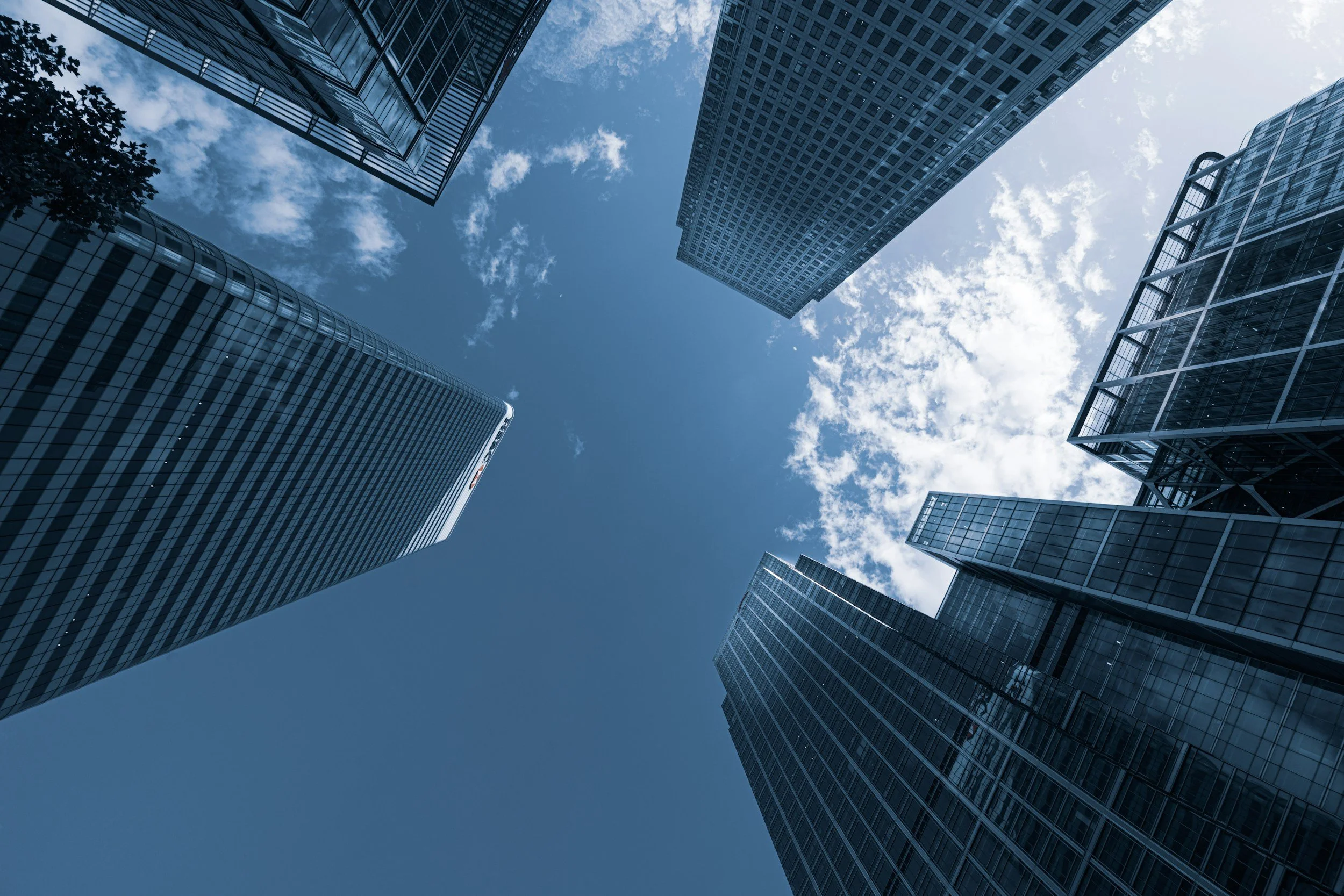 Looking up at tall glass skyscrapers against a partly cloudy sky.