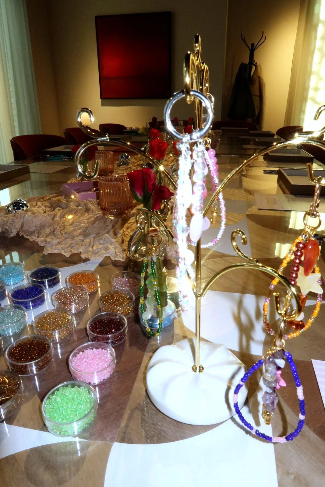 Charm display stand and pots of coloured seed beads on the table at a Petals & Pearls jewellery workshop.