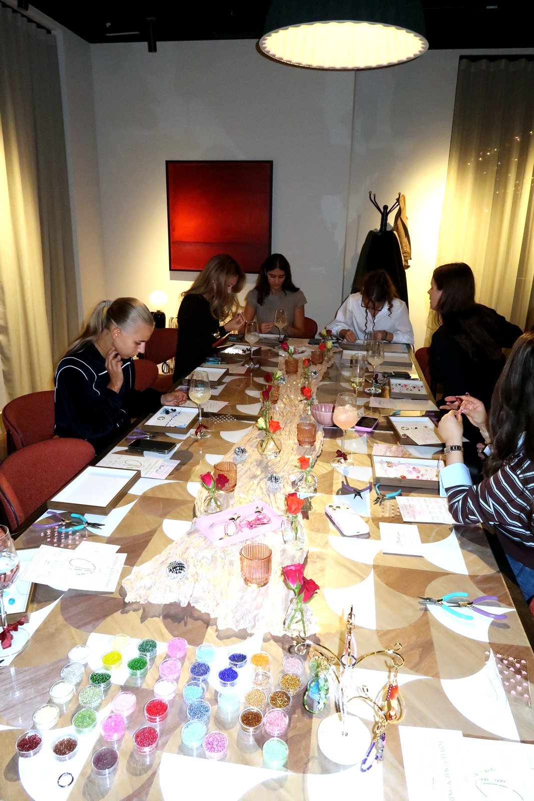 Guests making beaded jewellery at a Petals & Pearls private workshop for residents at Vertus, Canary Wharf. Long table set with bead pots, flowers and drinks.