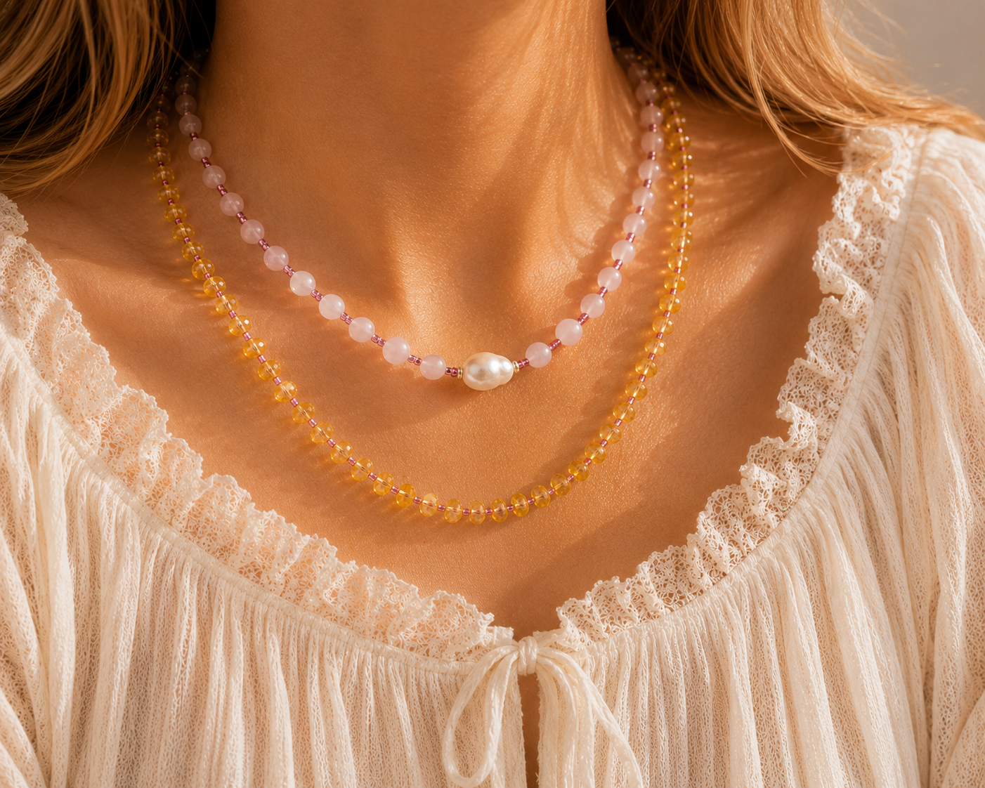 Layered pink and gold beaded necklaces with pearl accents worn with a soft white summer top.