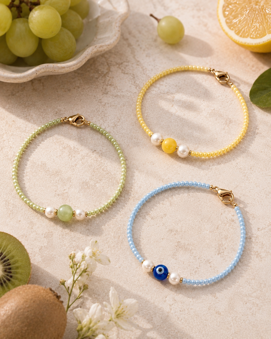 Three colourful handmade seed bead bracelets with pearl and charm details styled on a neutral stone surface.