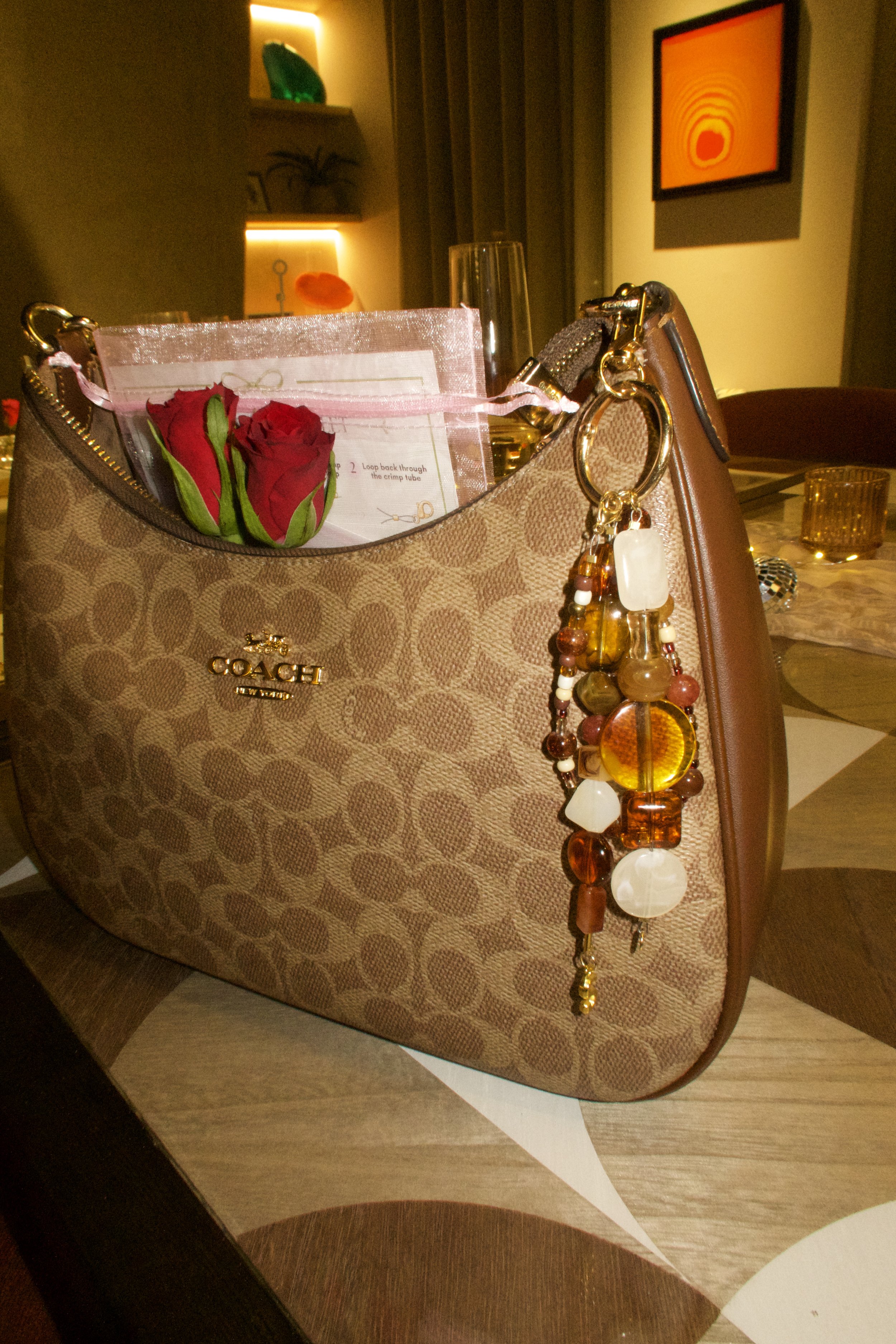 Handmade beaded bag charm keyring with amber, brown and cream statement beads and pearl details. Attached to a handbag.