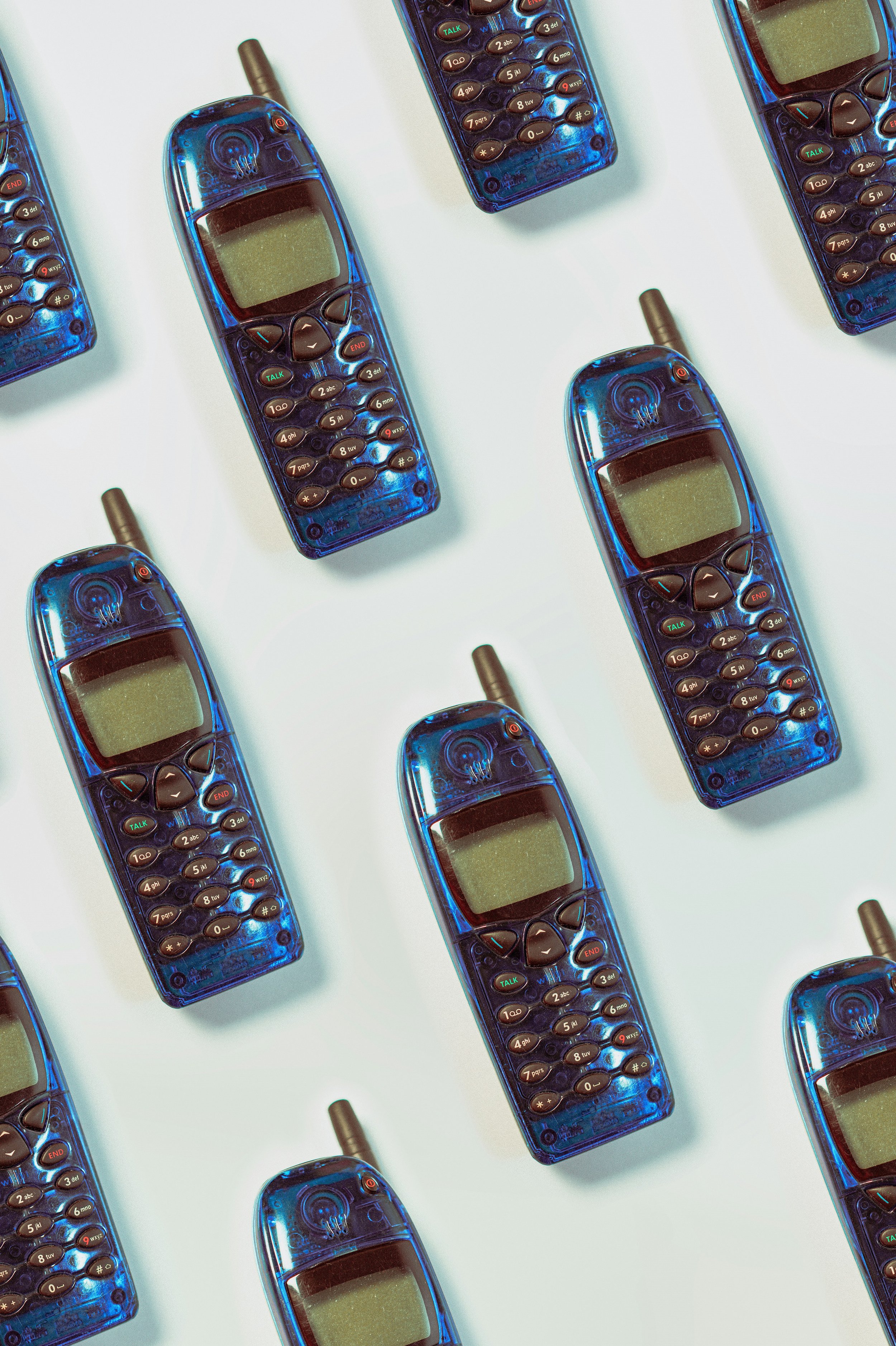 Mehrere alte Mobiltelefone in blauer Transparenzhülle auf weißem Hintergrund, aufgerichtet und quer gestellt.
