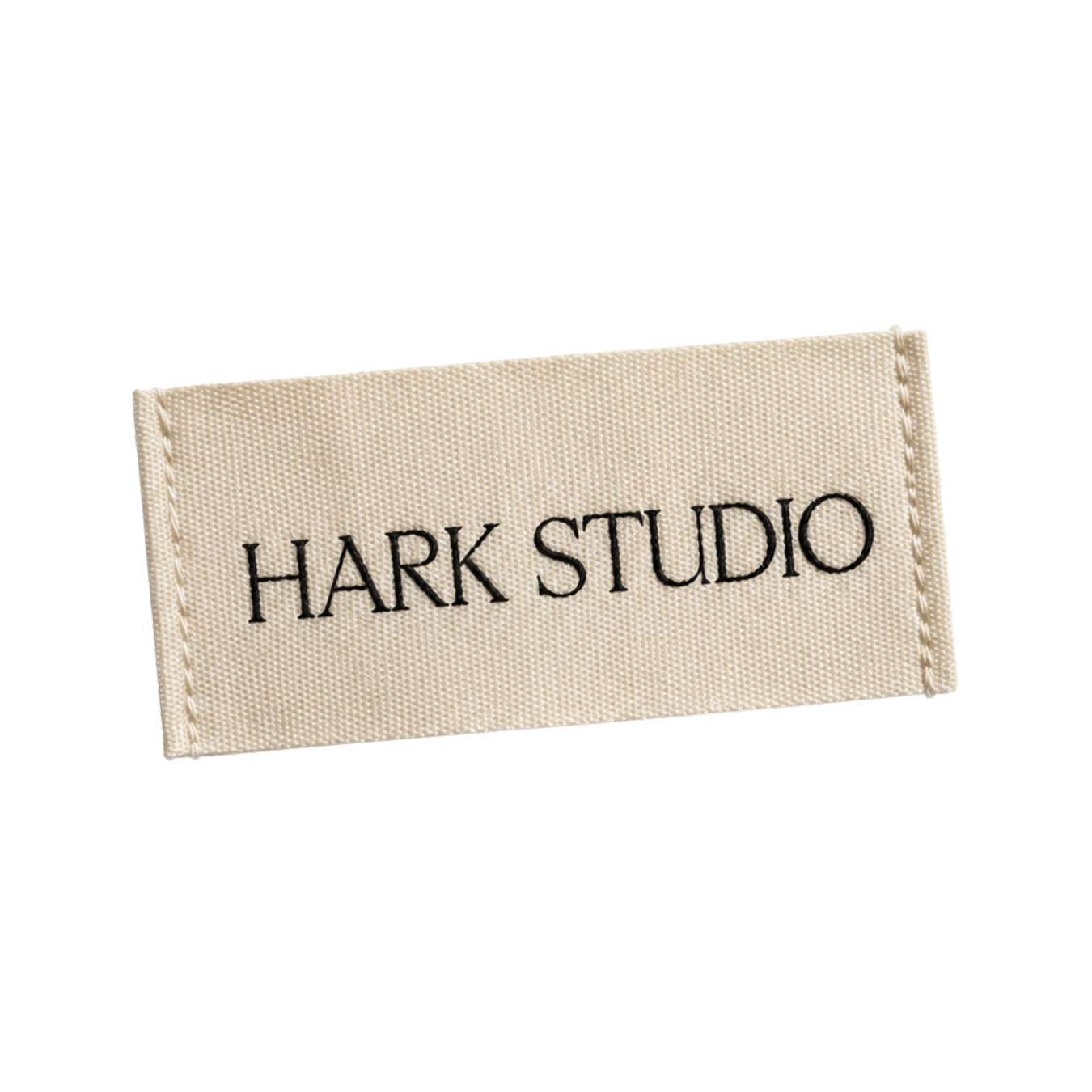 Close-up of a fabric label with the text "HARK STUDIO" embroidered in black on a beige background.