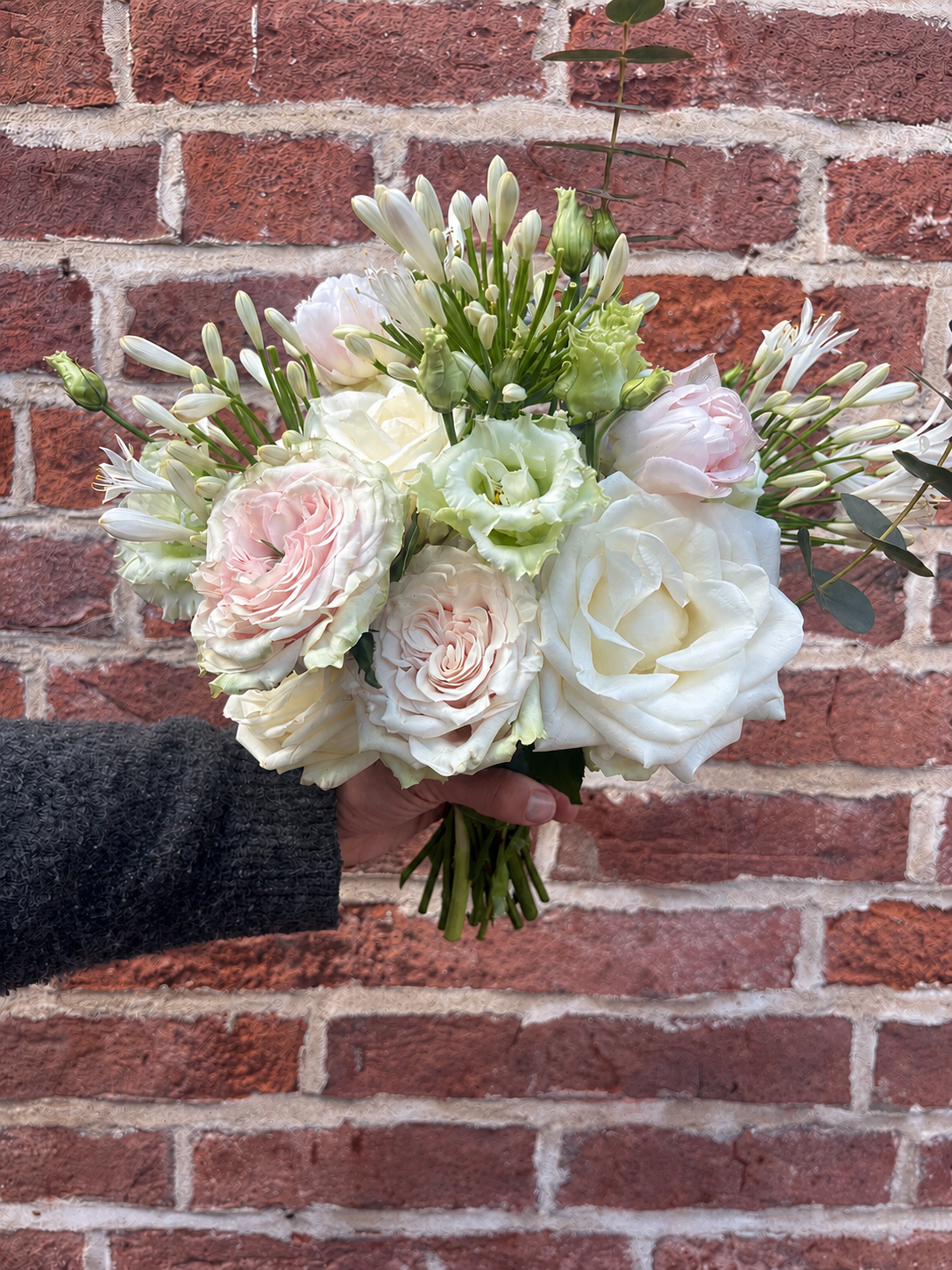 A beautiful bridesmaid bouquet of white and pale pink roses, lisianthus, and other flowers.