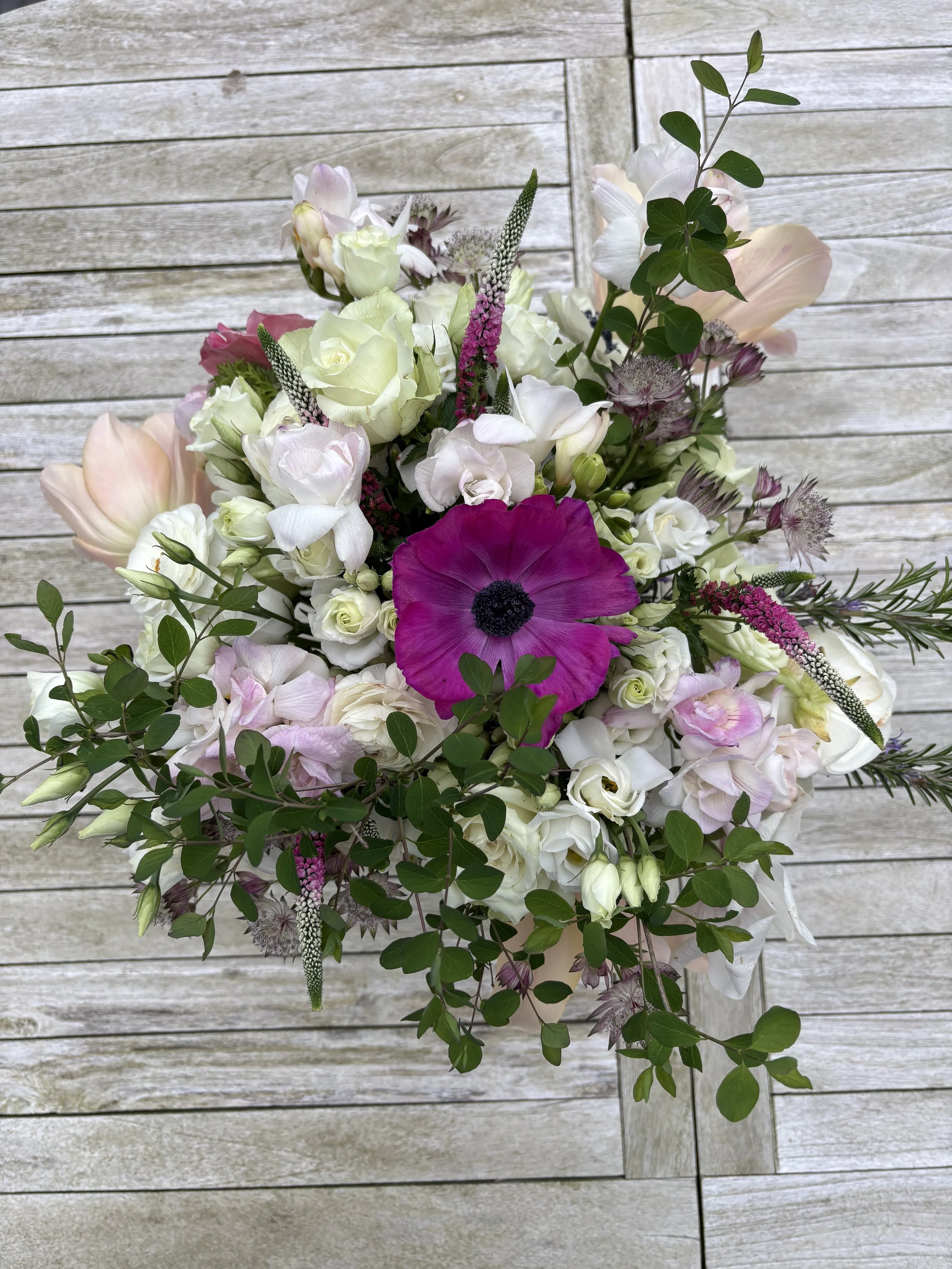 A stunning floral arrangement with white, pink, and purple flowers and green foliage.