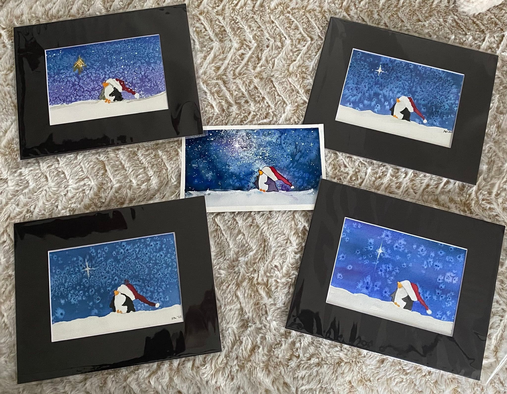 Christmas cards featuring penguins in a winter snow scene, with a starry blue sky background.