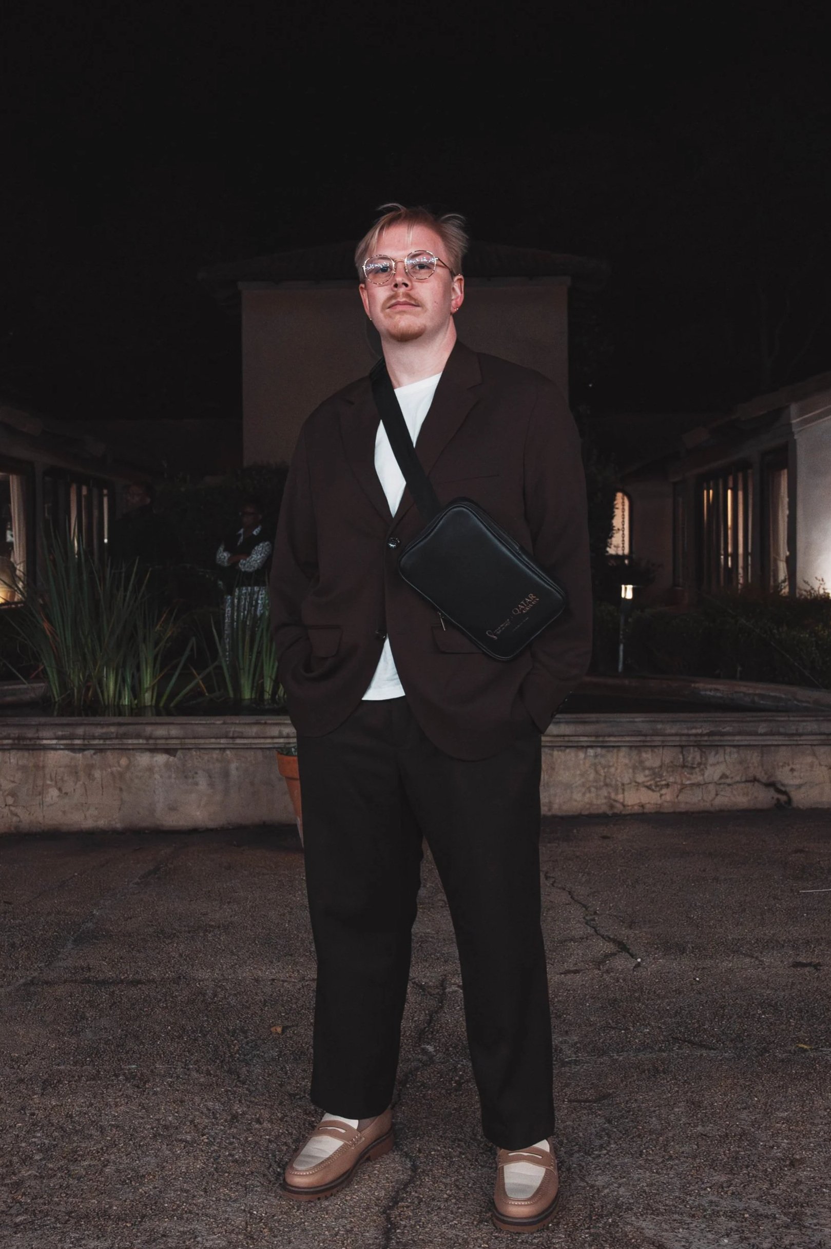 Specialist Wellness Counsellor Simon McCauley with glasses and a blazer standing outside a modern building.