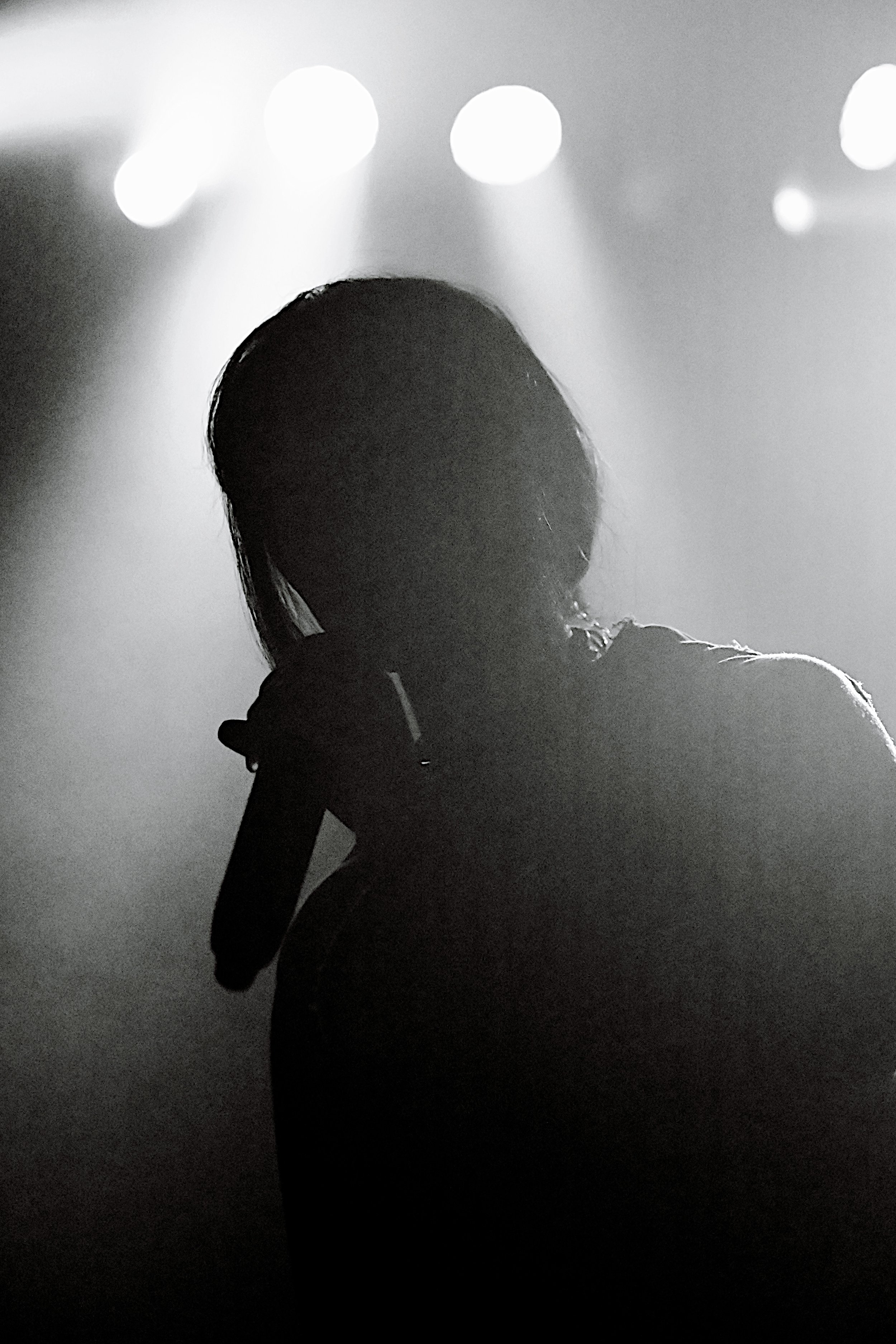 Silhouette of a person holding a guitar against a background of bright lights.