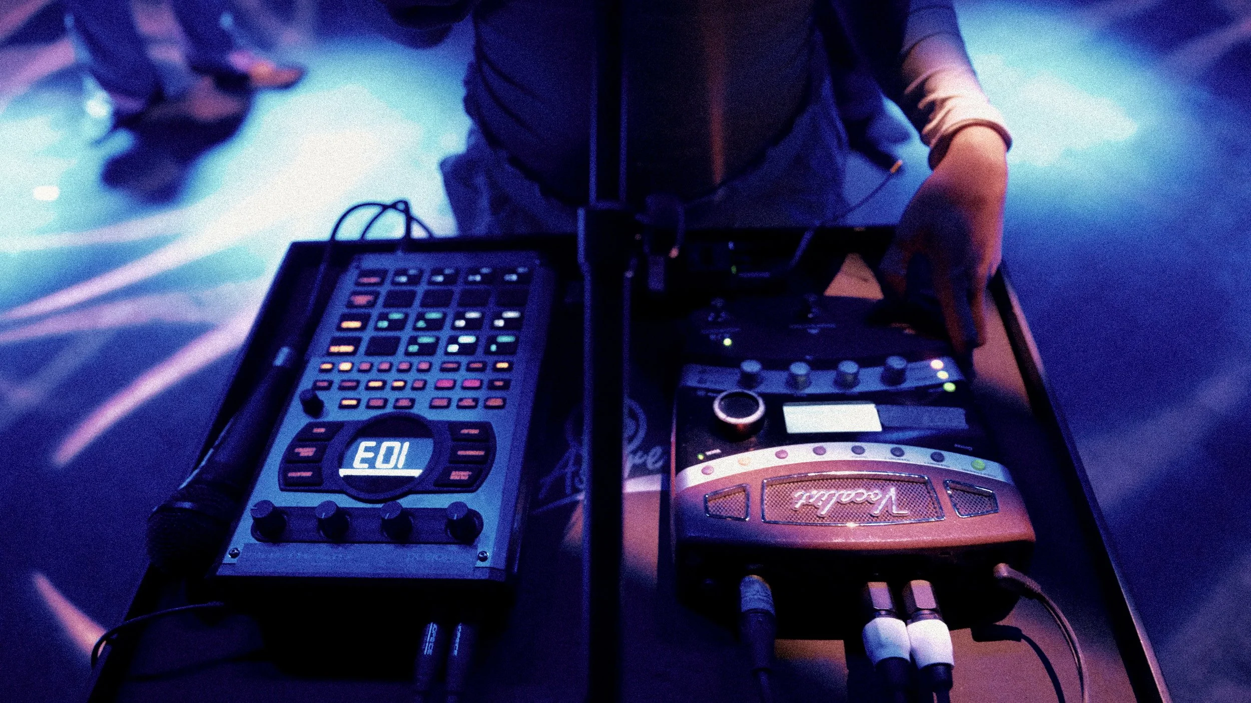 DJ equipment including a mixer and a turntable on a DJ booth with colorful lighting.
