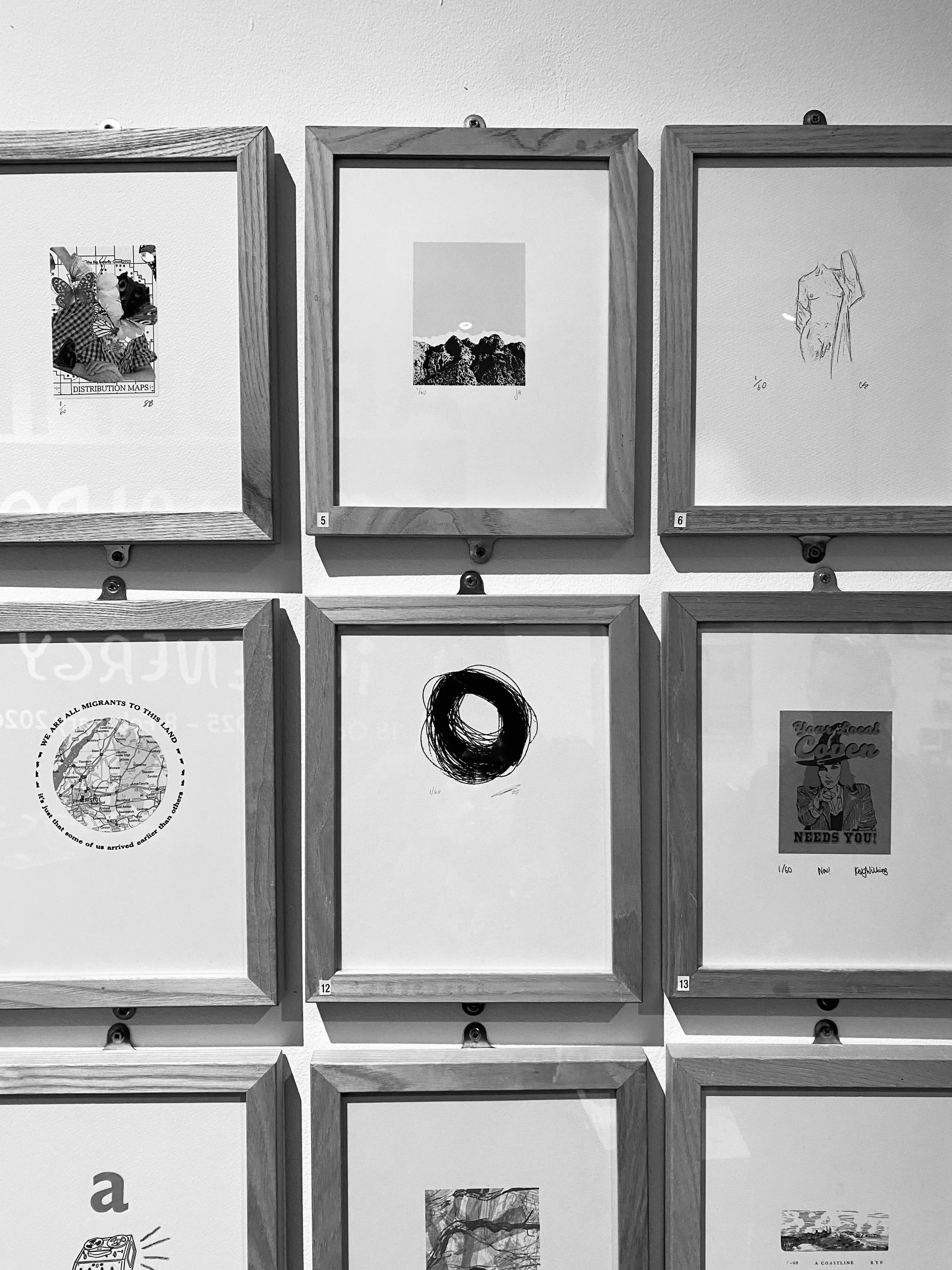 Black and white photo of six wooden picture frames on a wall, with various images and text inside each frame.