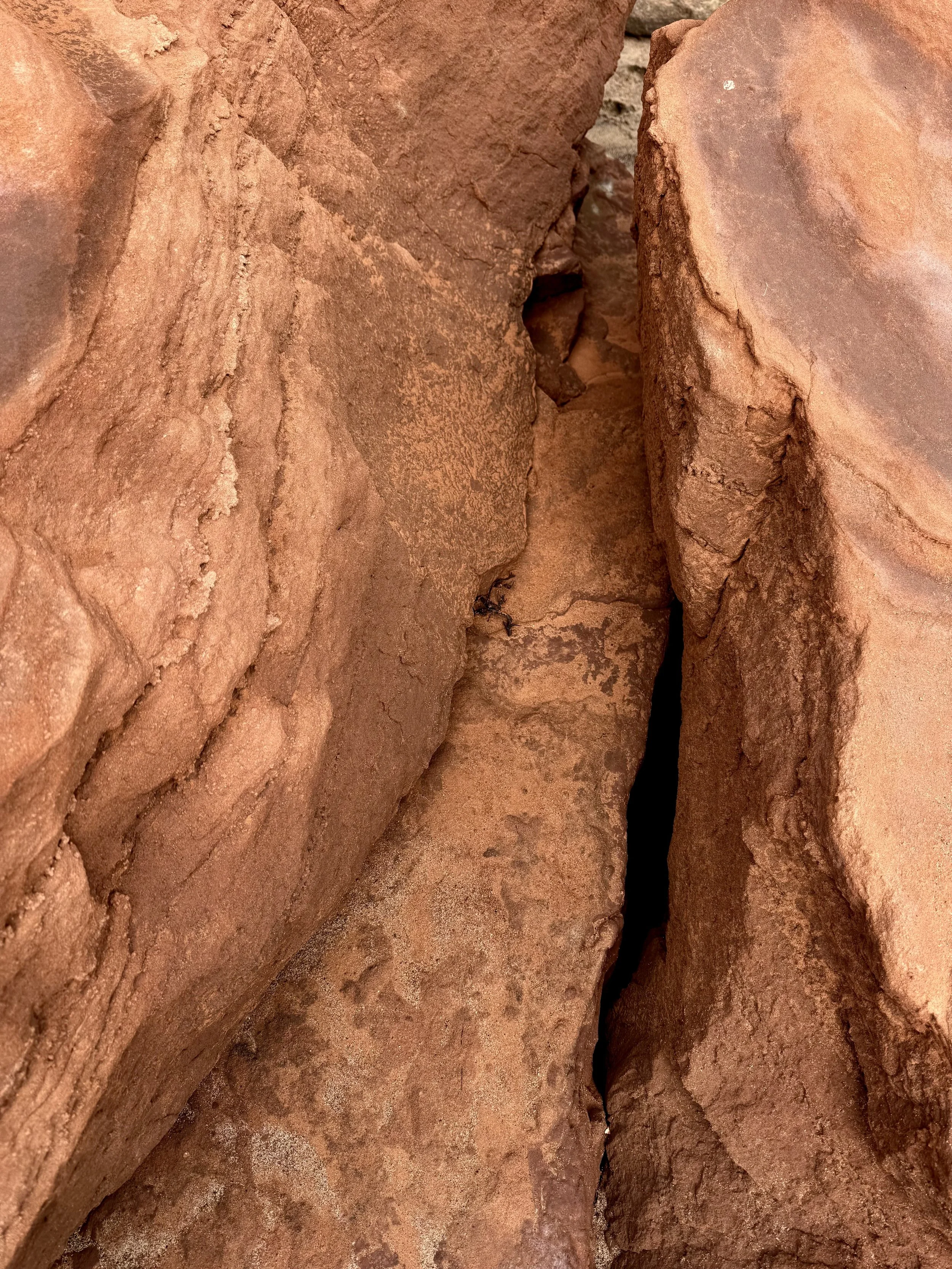 Close-up of reddish-brown rocks or bricks with a deep narrow crevice between them.