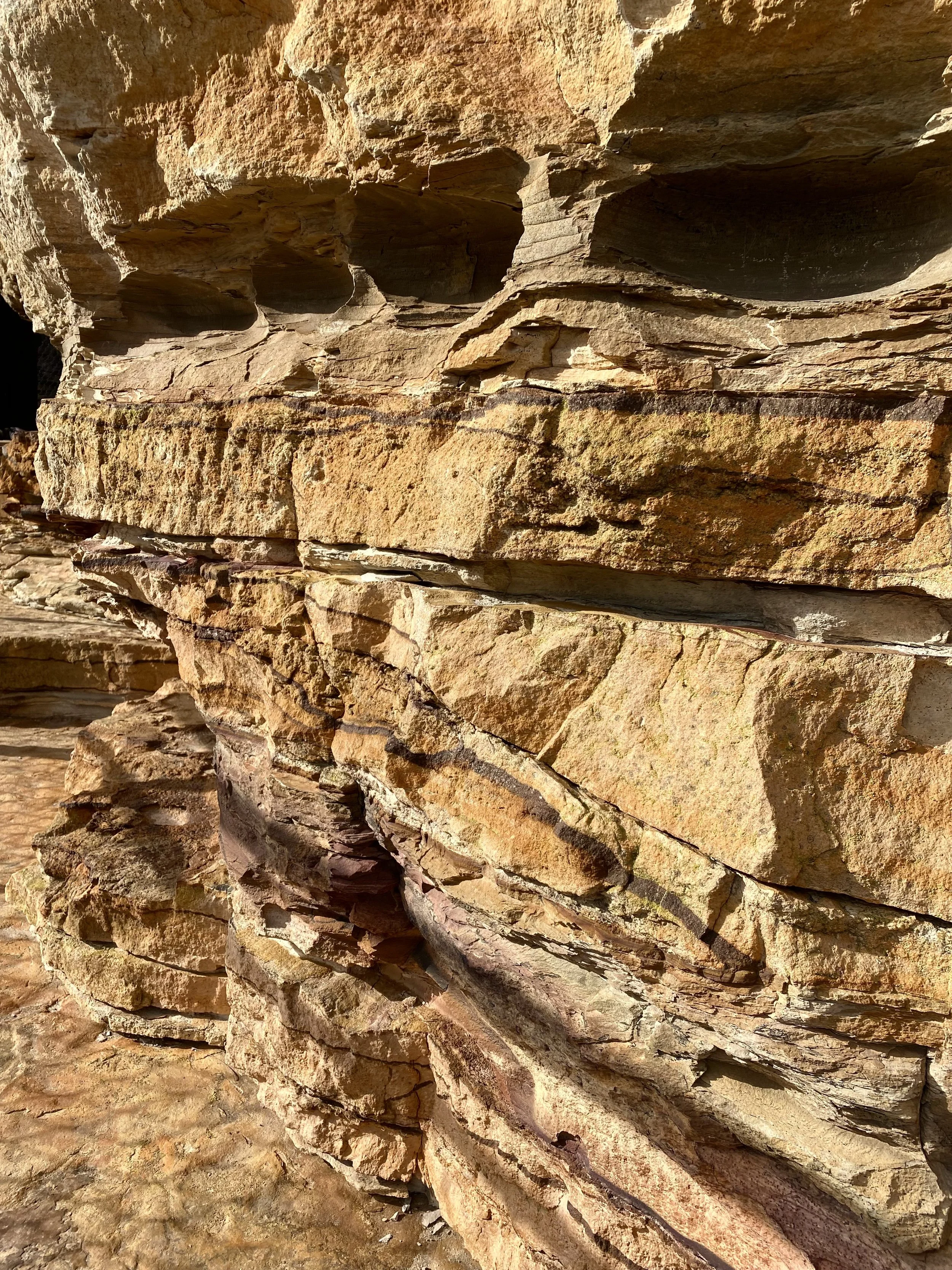 Close-up view of layered rocks with various textures and shades of brown and tan, showing natural erosion and geological formations.