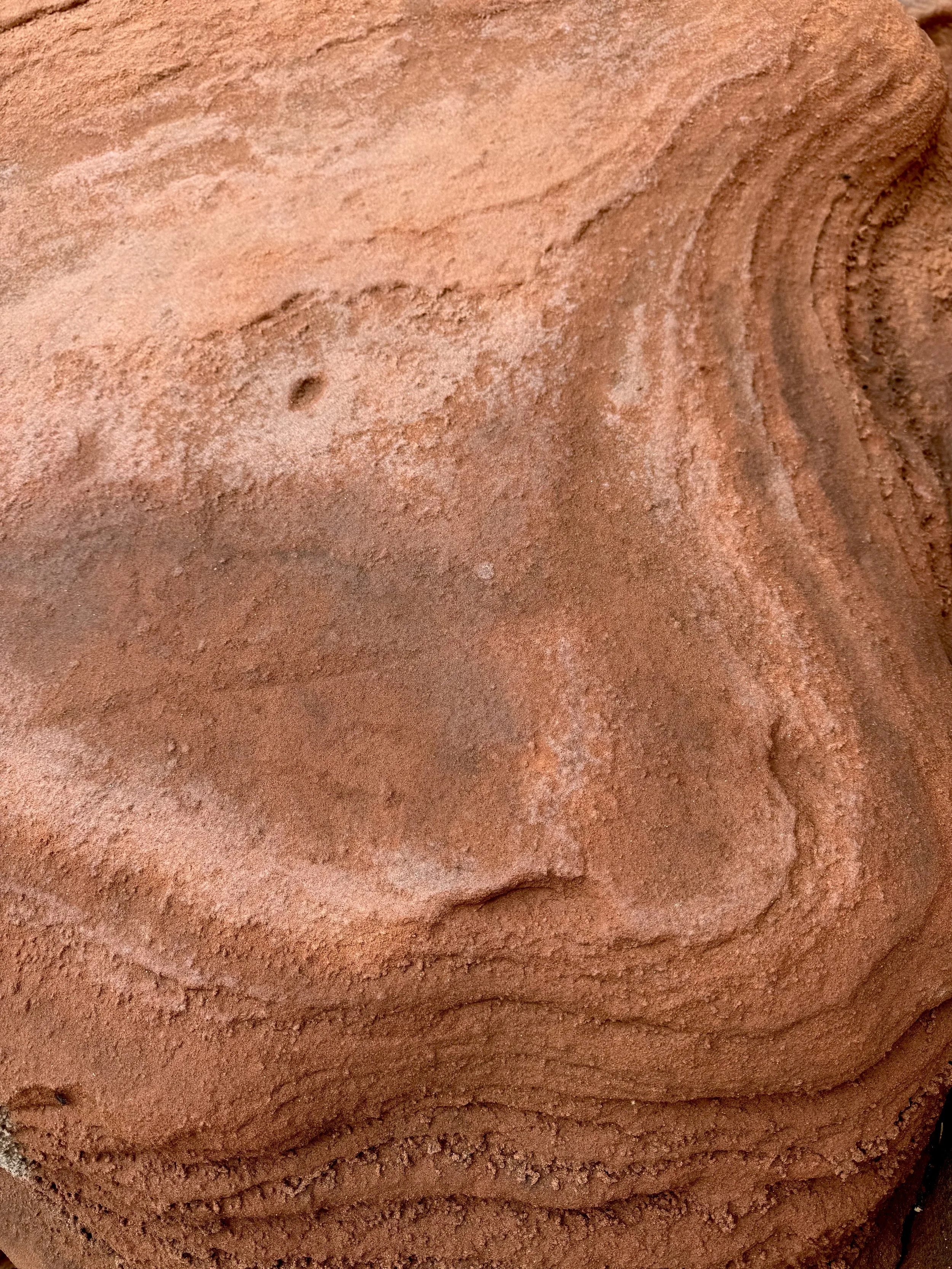 Close-up of pink powder, likely clay or pigment, with some textured areas and fine particles.