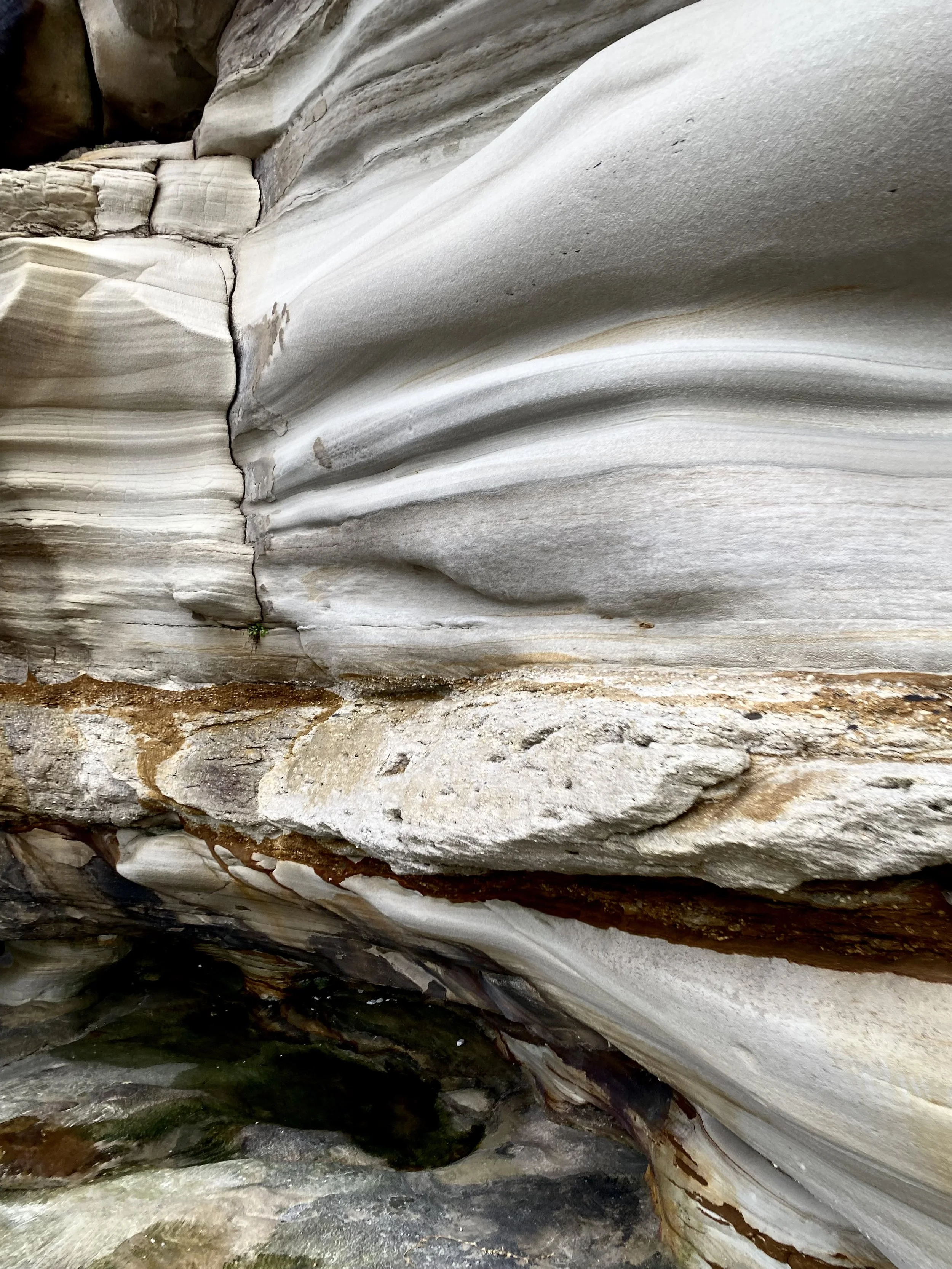 Close-up of layered, weathered rock formations with smooth, striated surfaces and earthy tones.