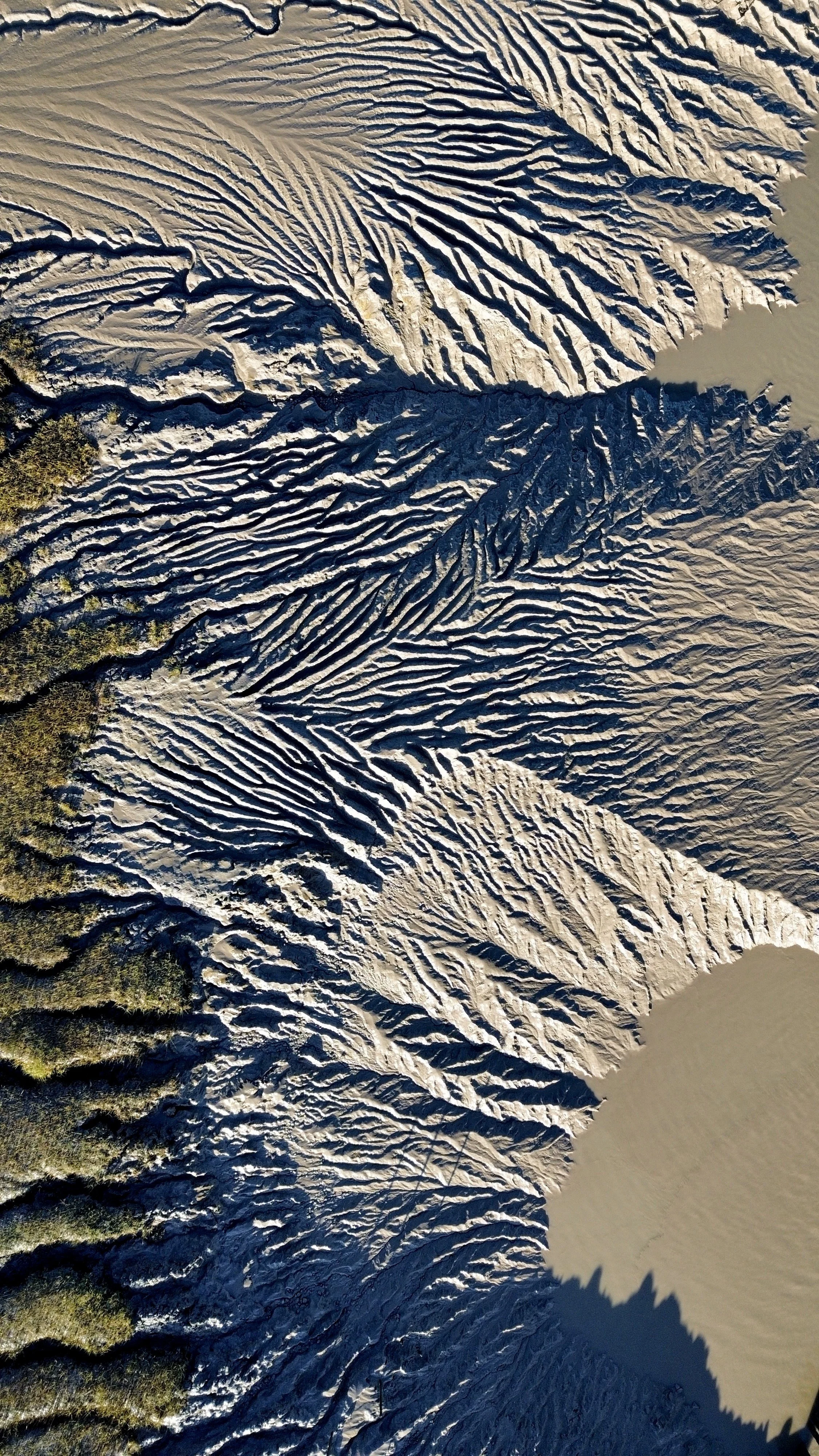 Aerial view of a landscape with snow-covered ridges and a body of water at the top right.