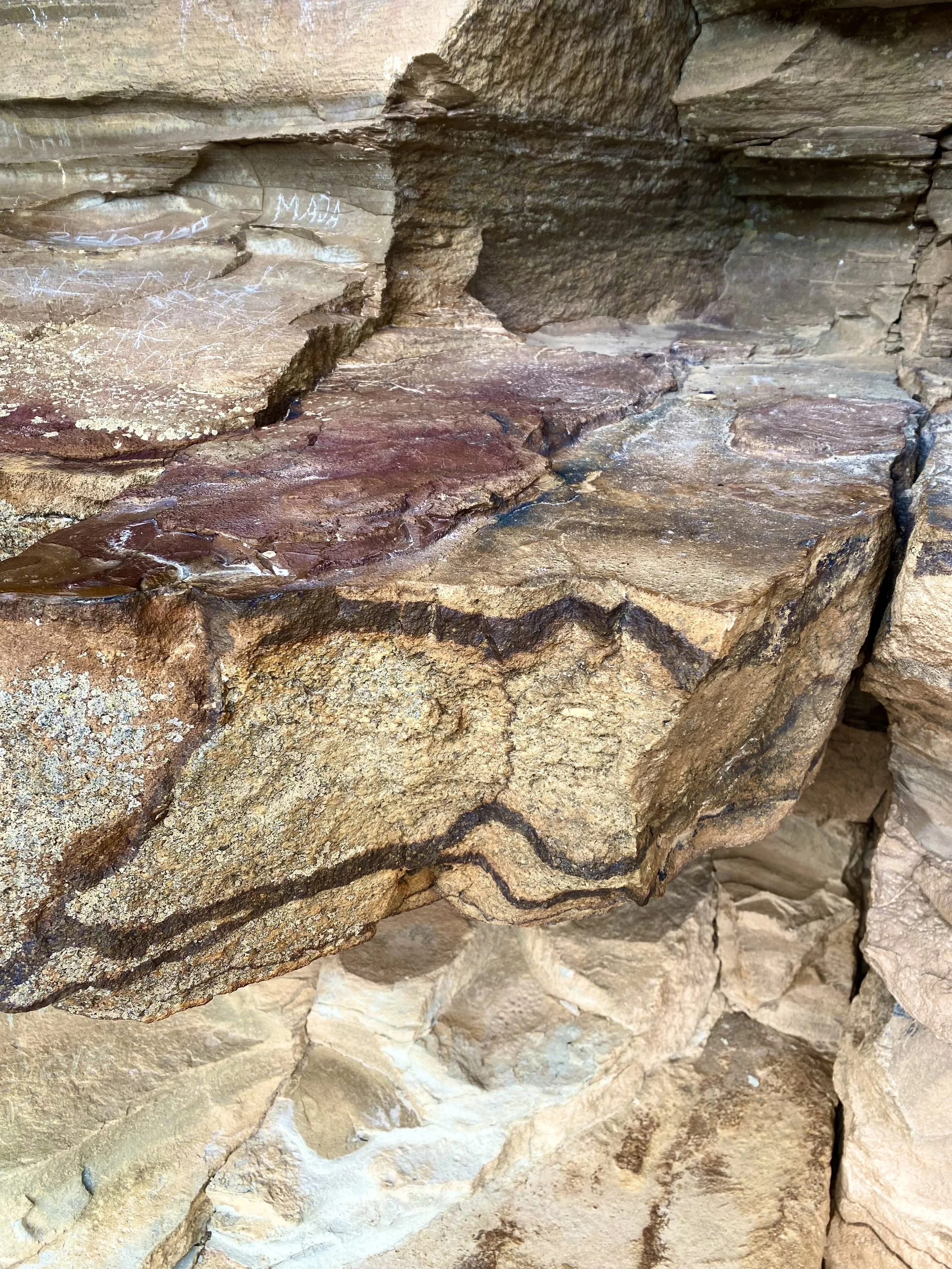 Close-up of layered sedimentary rocks with some chalk markings on the surface.