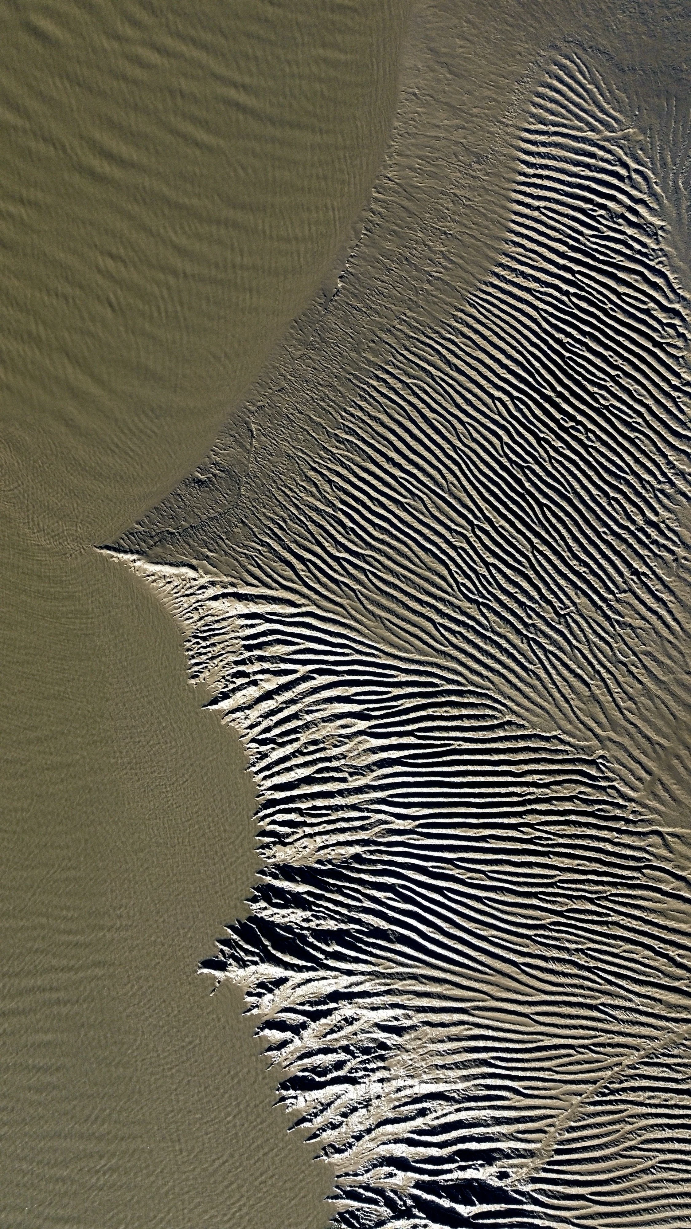 Aerial view of sand dunes with intricate patterns and ripples in the desert.