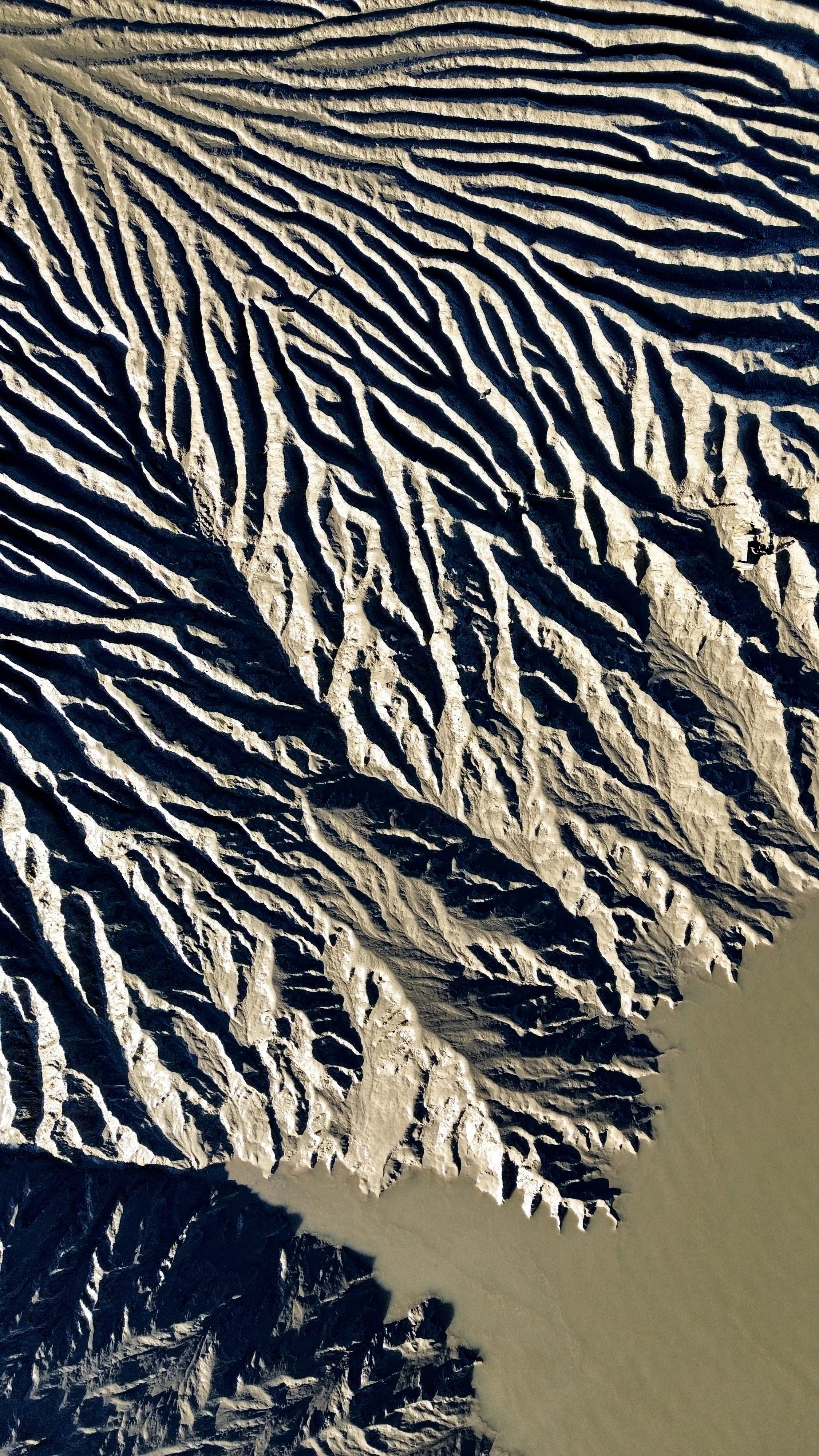 Aerial view of snow-covered mountain peaks and ridges with a river flowing through a valley.