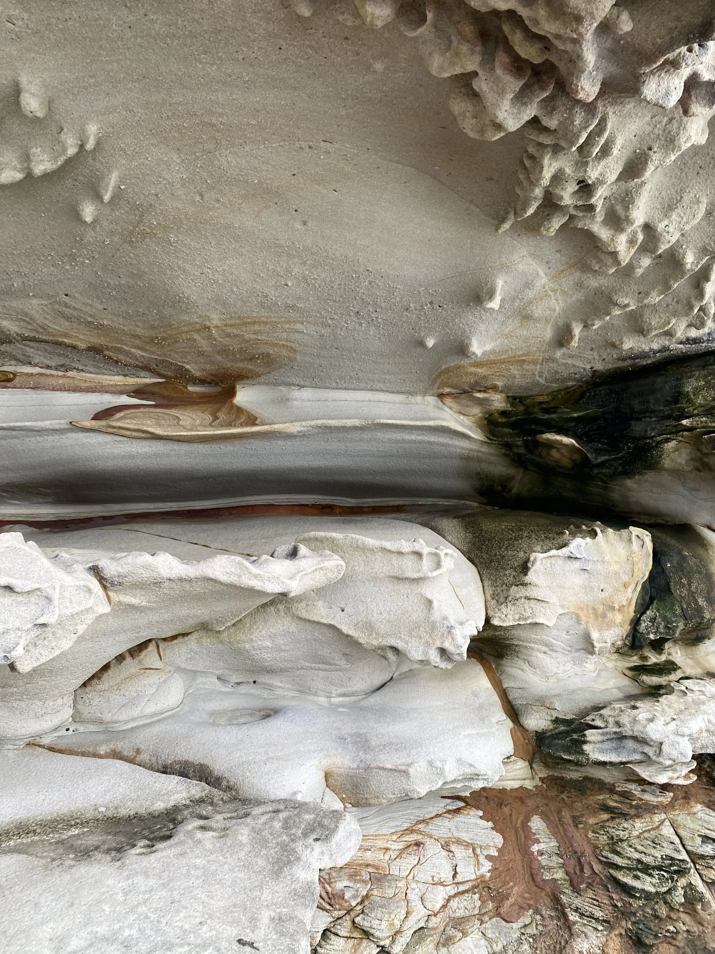 Close-up view of layered, textured rocks with various colors and patterns, including shades of white, gray, brown, and black.