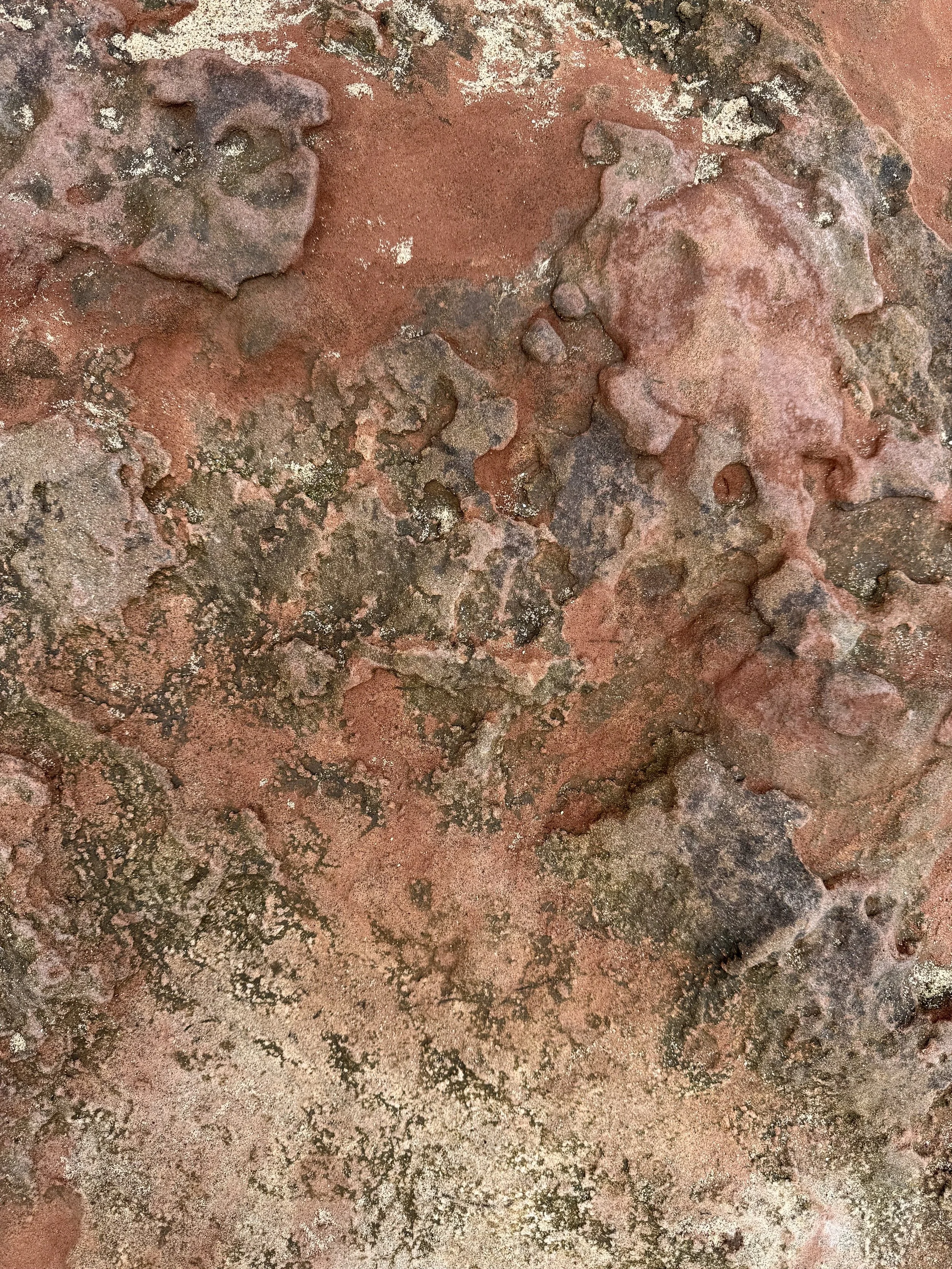 Close-up of a weathered, reddish-brown metal surface with patches of black and white corrosion.