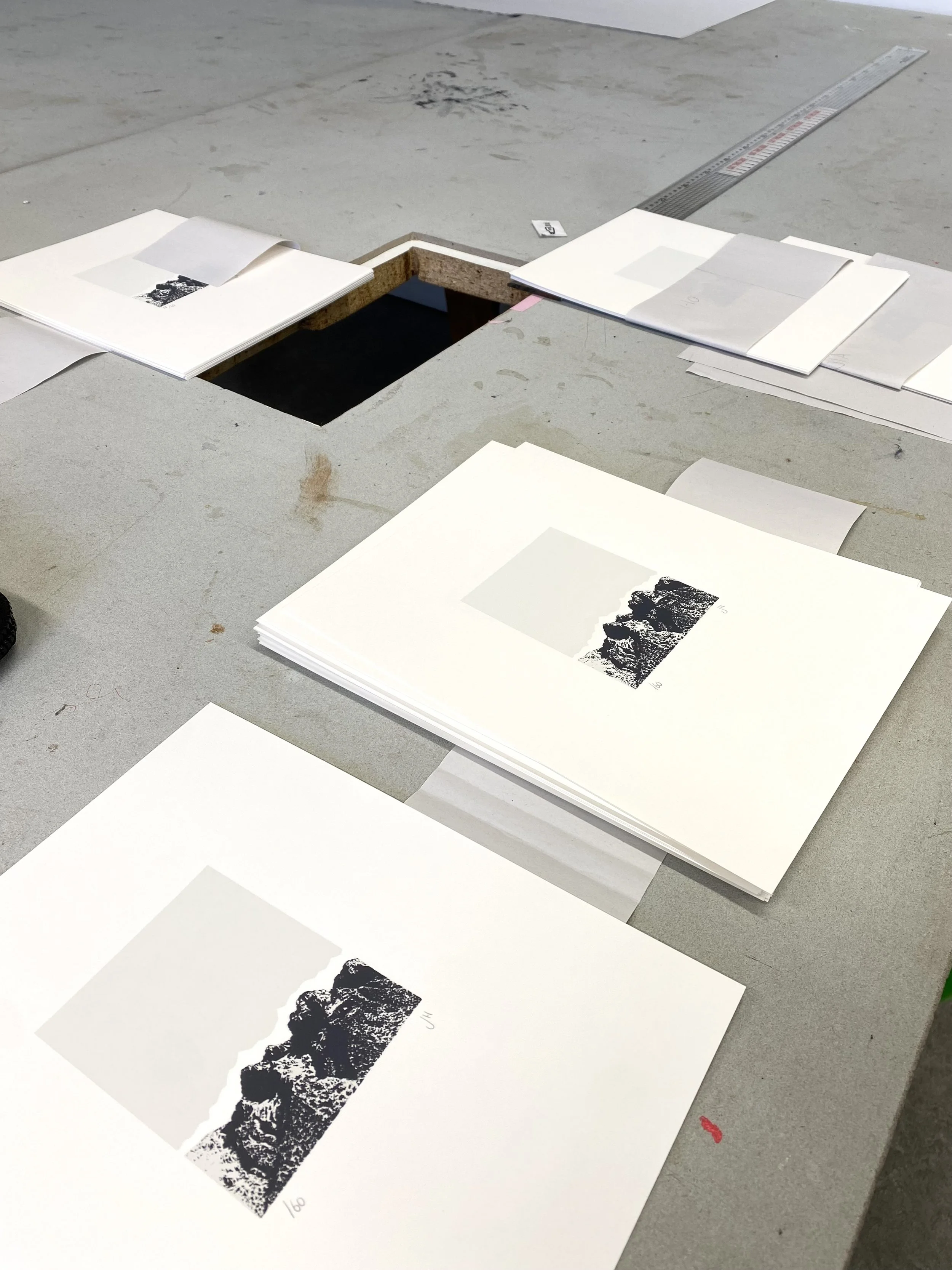 Printed prints of mountain landscapes placed on sheets of paper and laid on a flat surface, with a measuring ruler in the background.