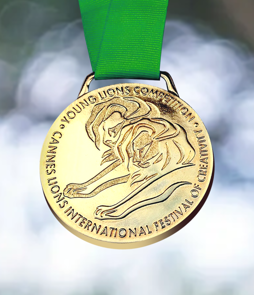 Sodiq Sheu Gold medal with a green ribbon, engraved with a lion's head and the text 'Young Lions Competition Cannes Lions International Festival of Creativity' around the edge.