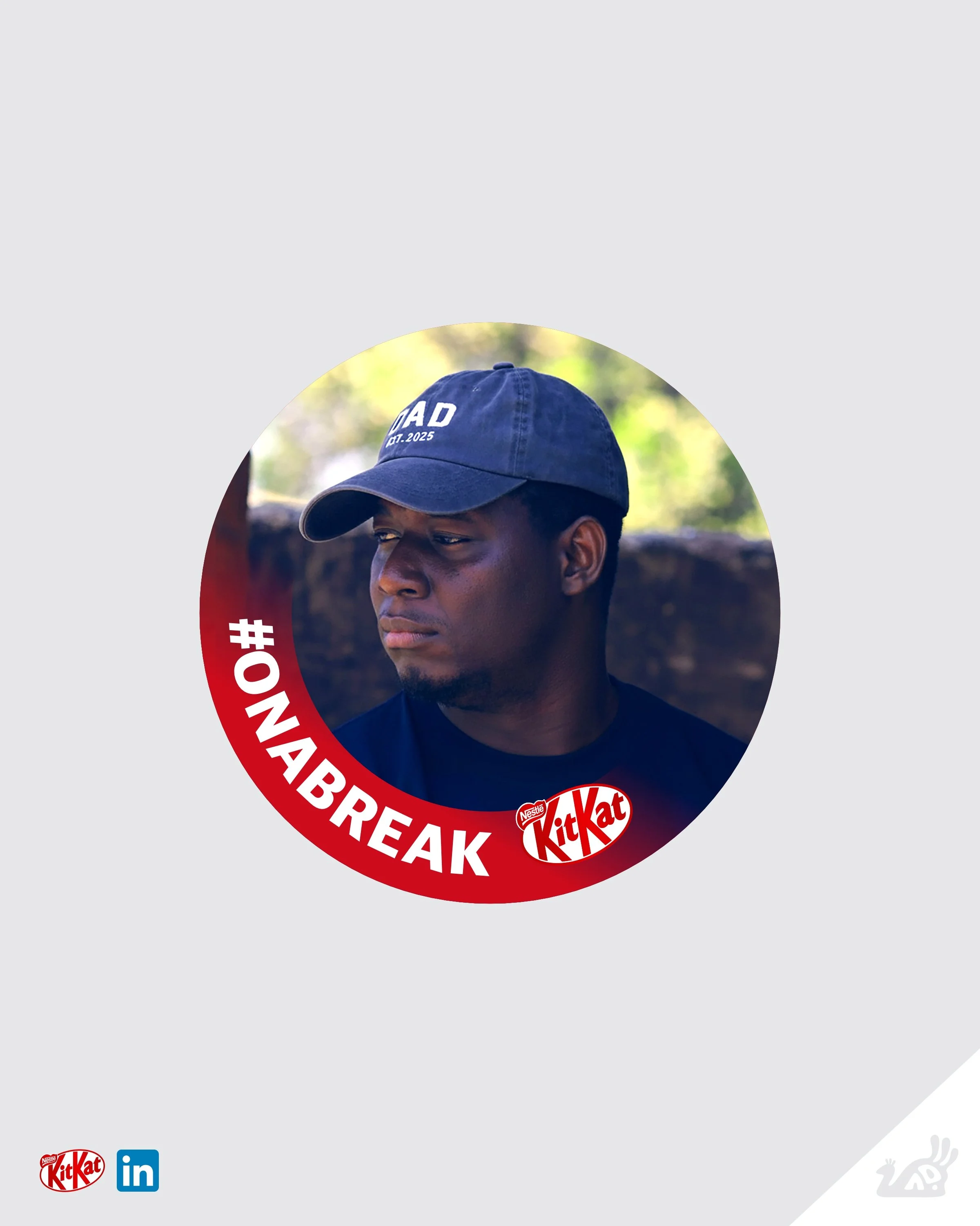 Partially visible person wearing a navy blue cap with white text, outdoors with blurred greenery in the background. KitKat Spec Ad.