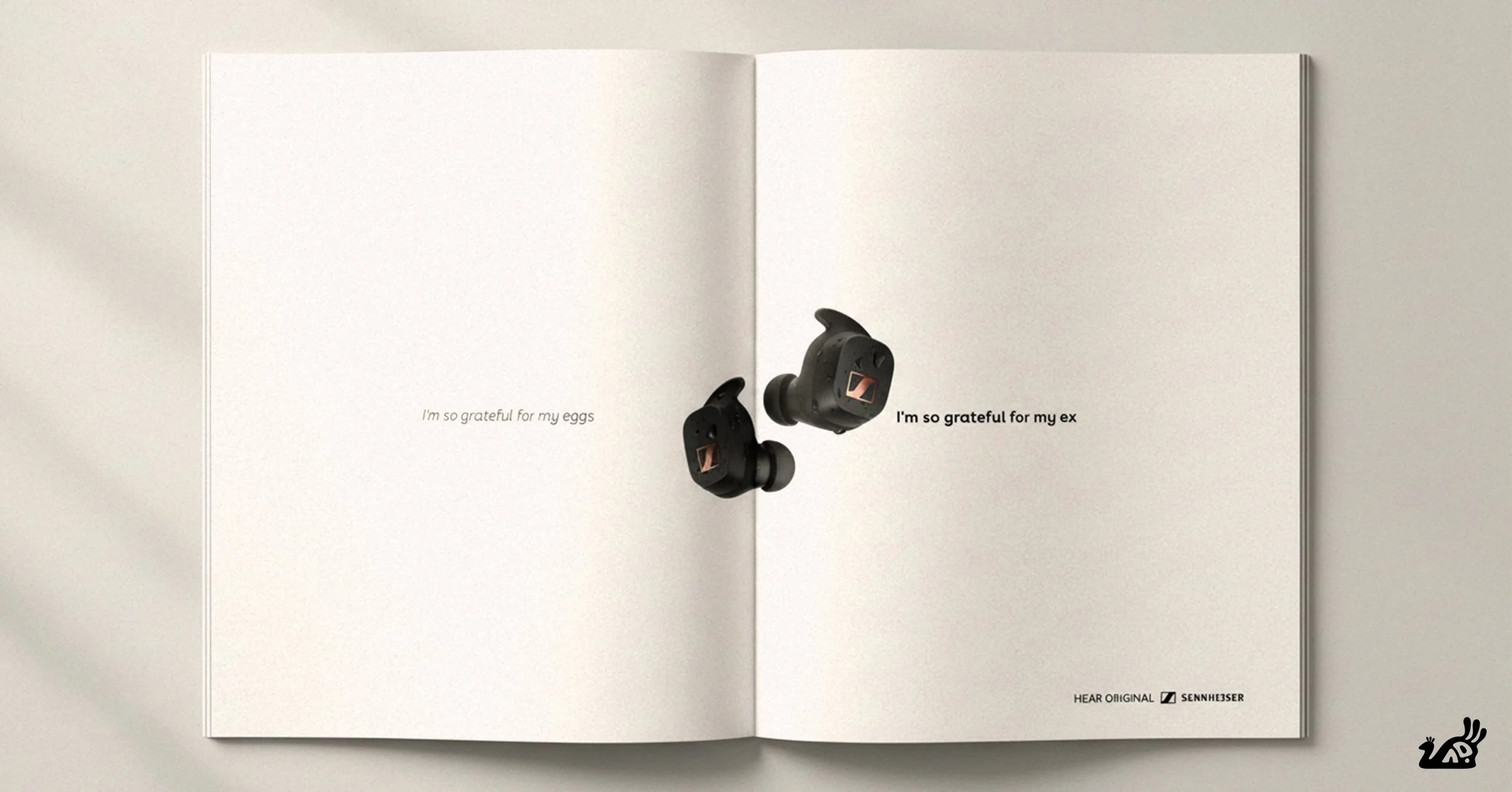An open book with a pair of black wireless earbuds attached to the right page. The left page has the text "I'm so grateful for my eggs" and the right page has the text "I'm so grateful for my ex." There is also small text at the bottom right corner that says "HEAR ORIGINAL SENNHEISER."