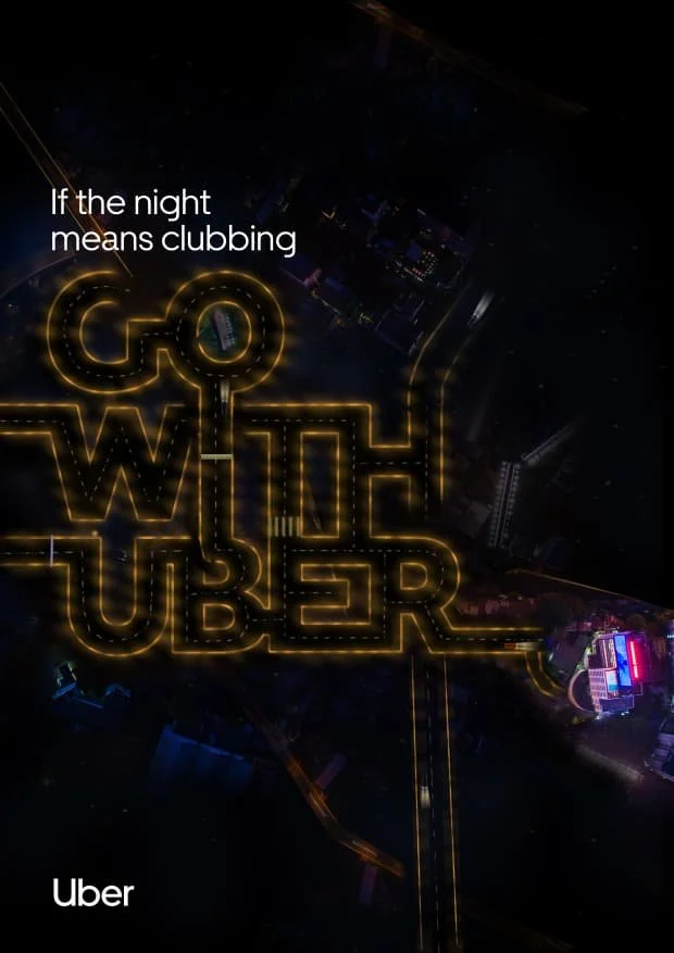 Nighttime aerial view of downtown with a large illuminated sign that reads 'Go with Uber' in yellow neon lights. There are city buildings and streets visible in the dark. The image includes the text 'If the night means clubbing' at the top and 'Uber'