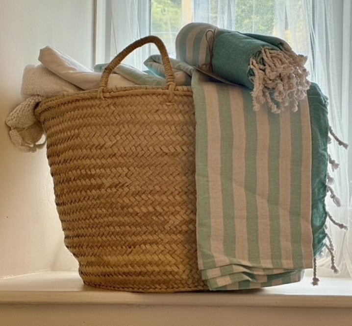 Luxury towels and blankets in a woven basket at Cobble Cottage holiday let, Cornwall