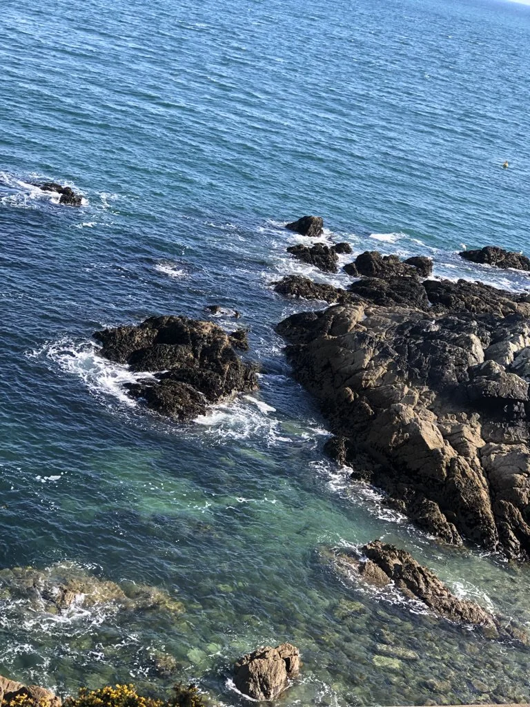 Rocky shoreline with clear blue water and small waves in the ocean