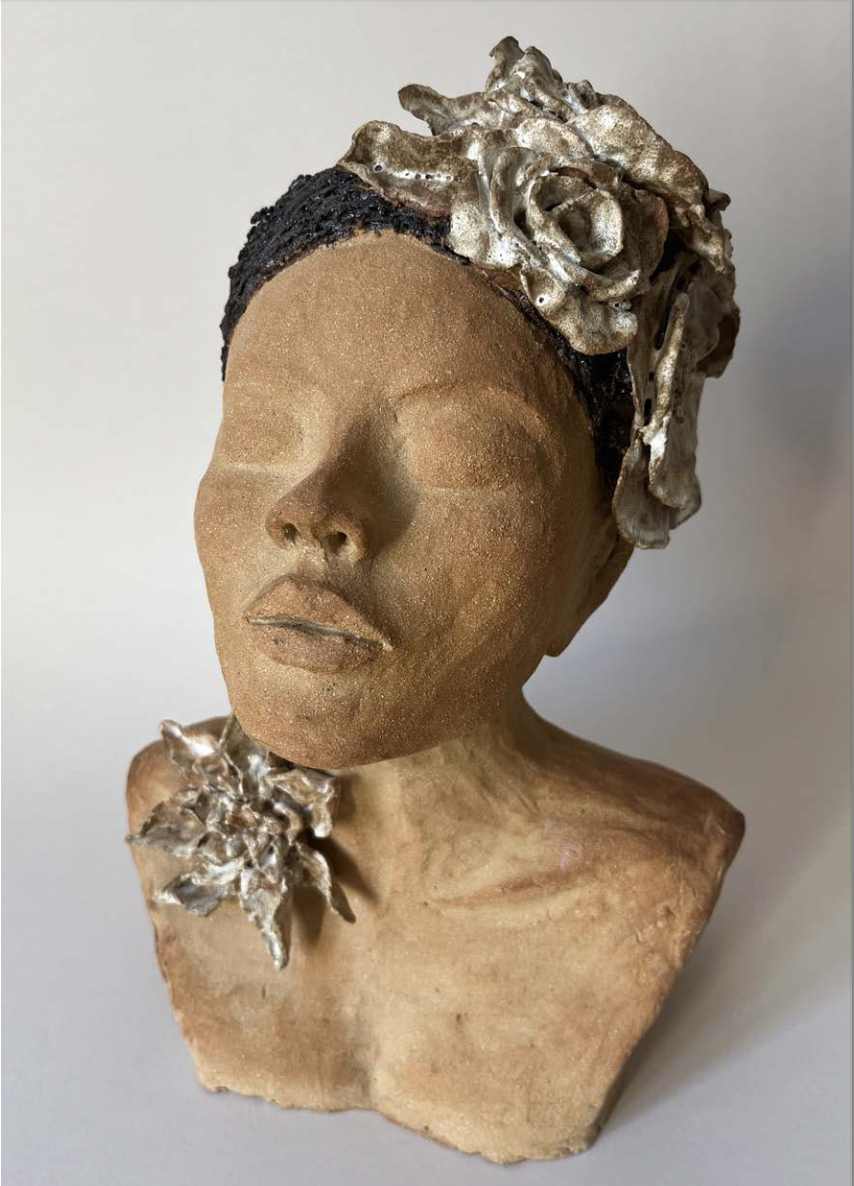 Statue en terre d'une femme avec des fleurs en relief sur la tête et sur l'épaule.
