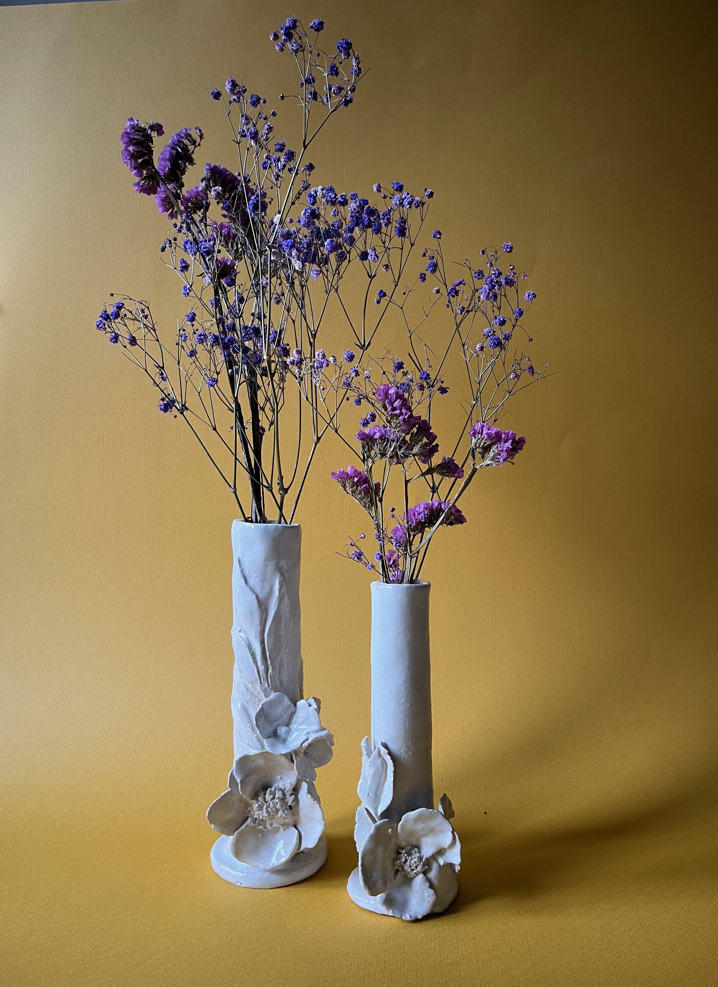 Vase blanc avec fleurs séchées violettes et mauves, fond jaune
