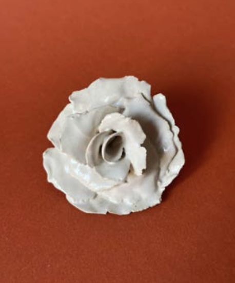Une rose blanche en relief contre un fond rouge.