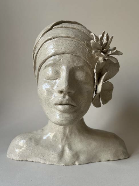 Statue en céramique représentant une tête de femme avec un turban, décorée d'une grande fleur en poterie sur le côté droit.