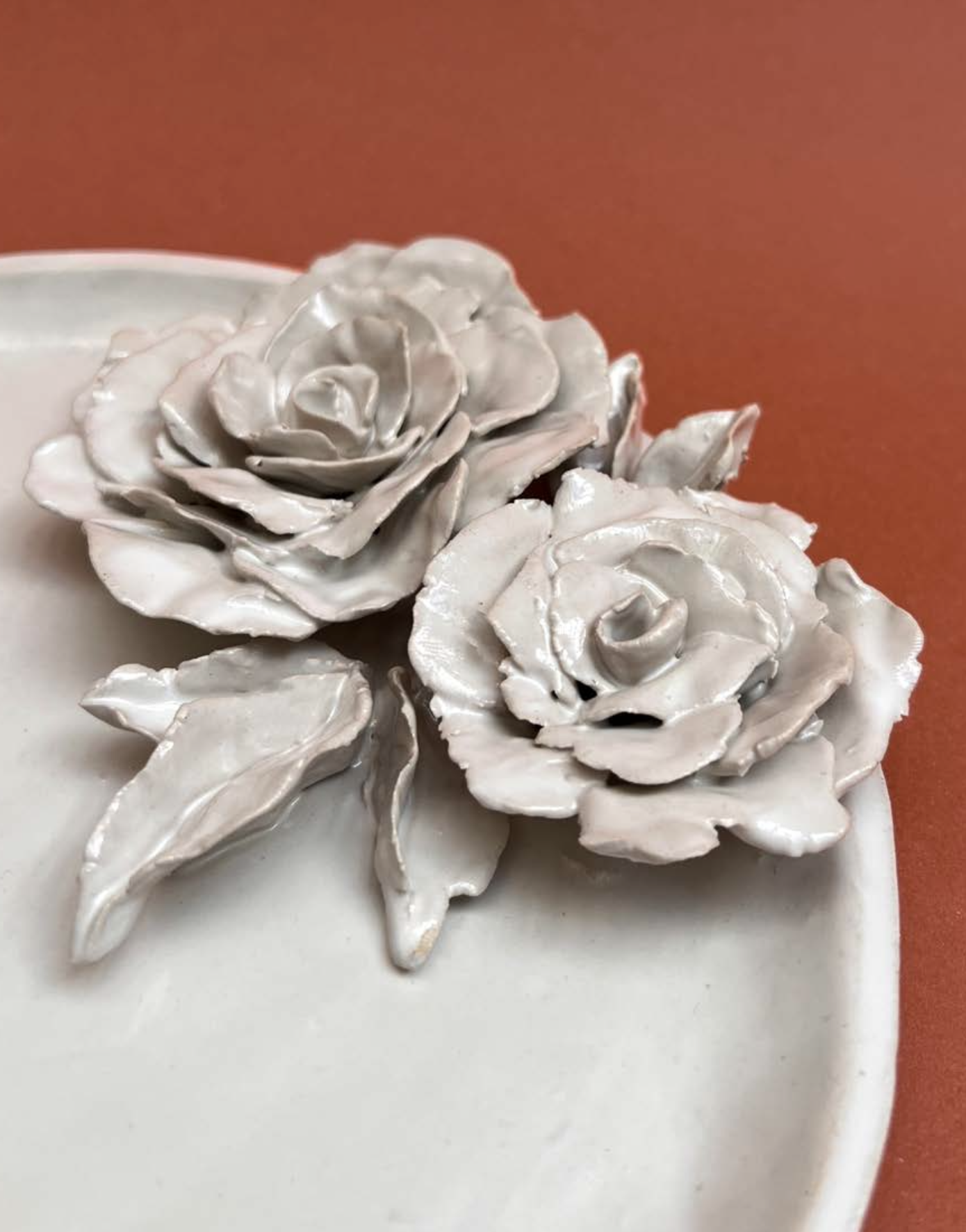 Décoration florale en forme de rose en matériau blanc, placée sur un gâteau blanc, avec un fond orange.
