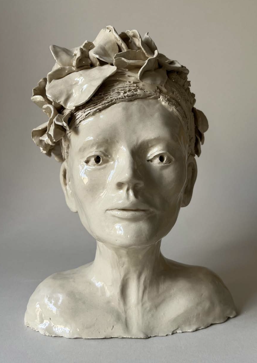 Buste en céramique d'un visage féminin, avec des cheveux sculptés en forme de fleurs ou de feuilles, de couleur beige ou ivoire.