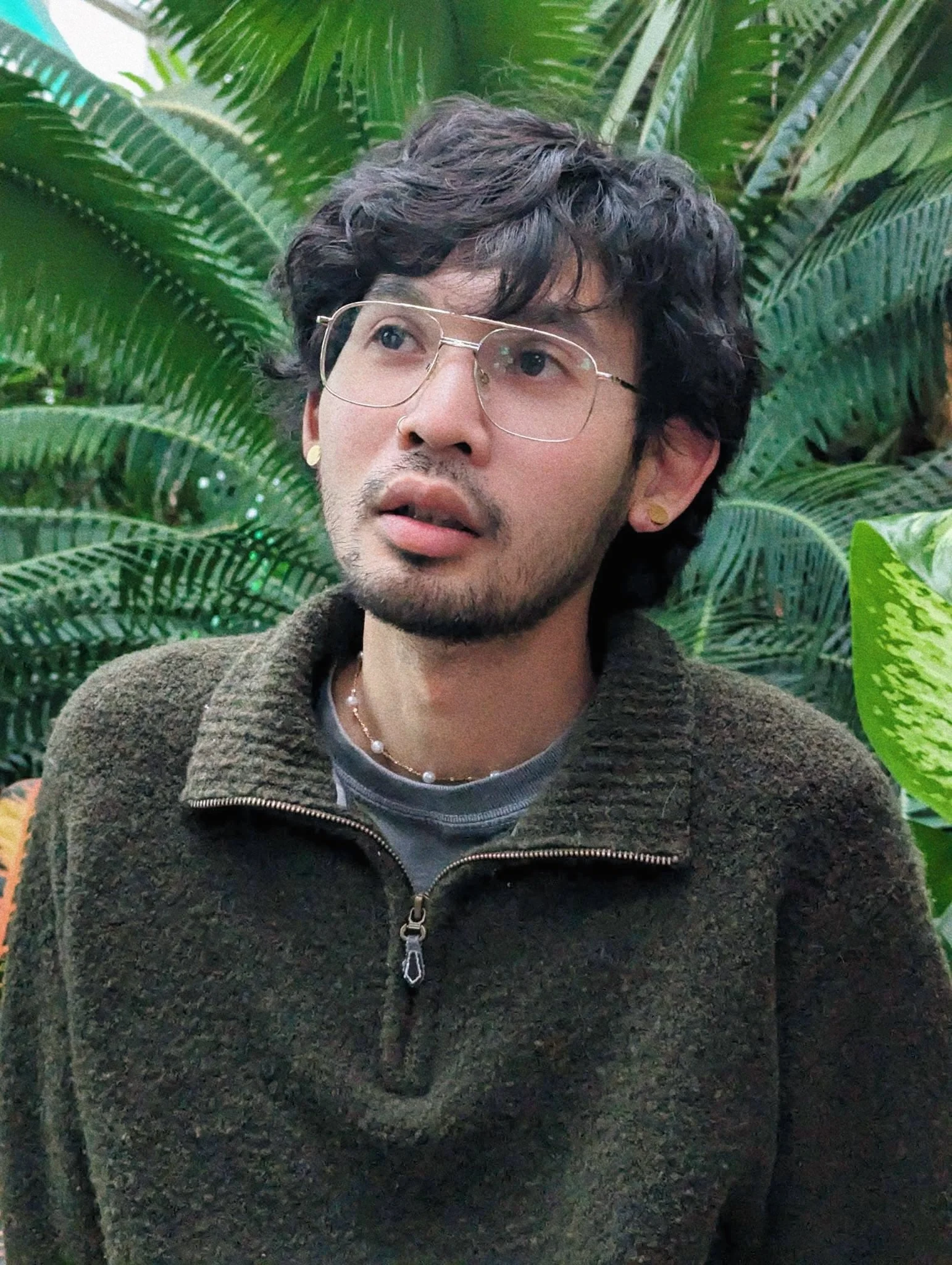 Seth Trowbridge, member at large of the Healing Feast Foundation, has a reflective gaze as he stares upward with fern-like plants in the background behind him