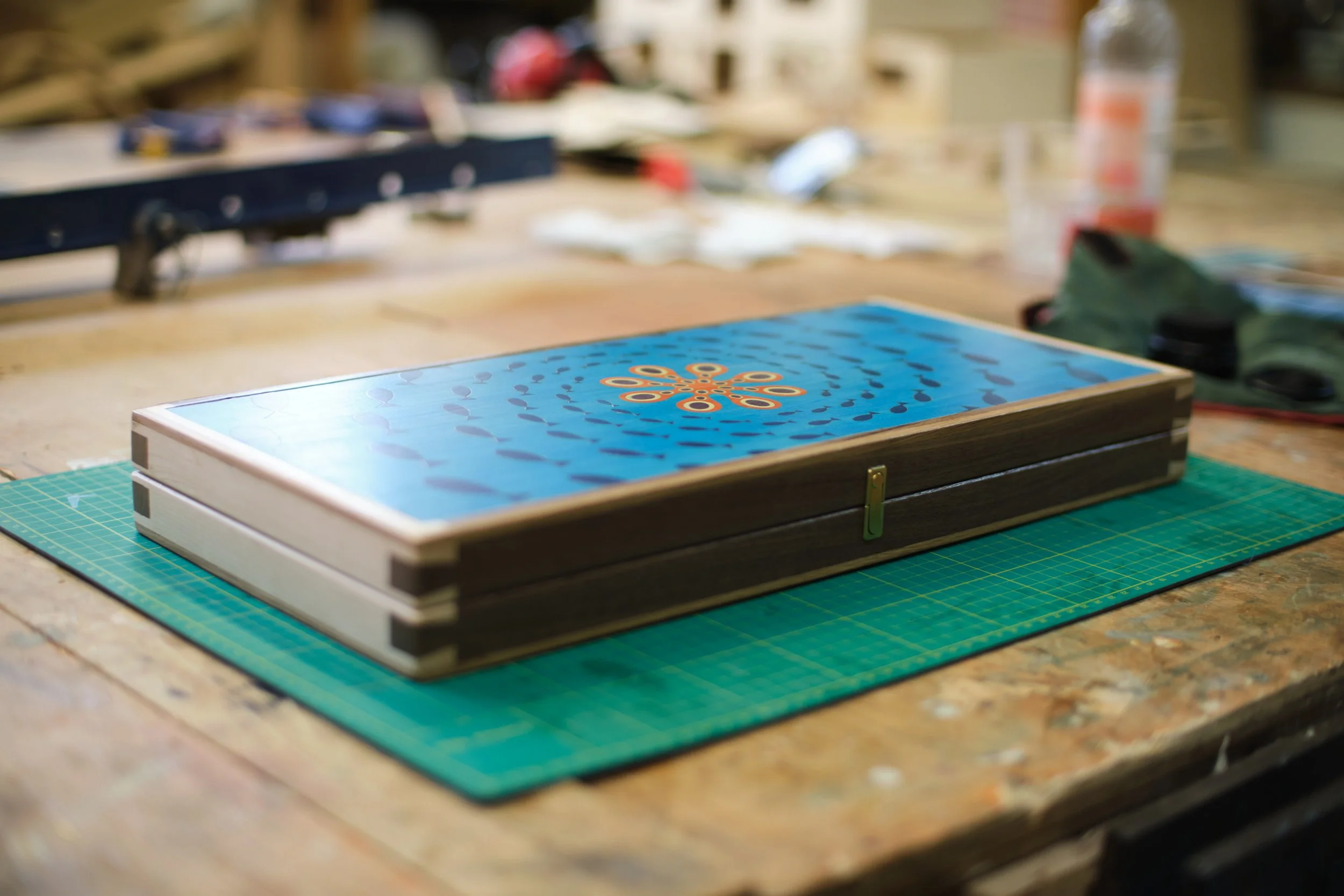 Close-up of a game box on a wooden workbench, with various crafting tools and materials in the background.