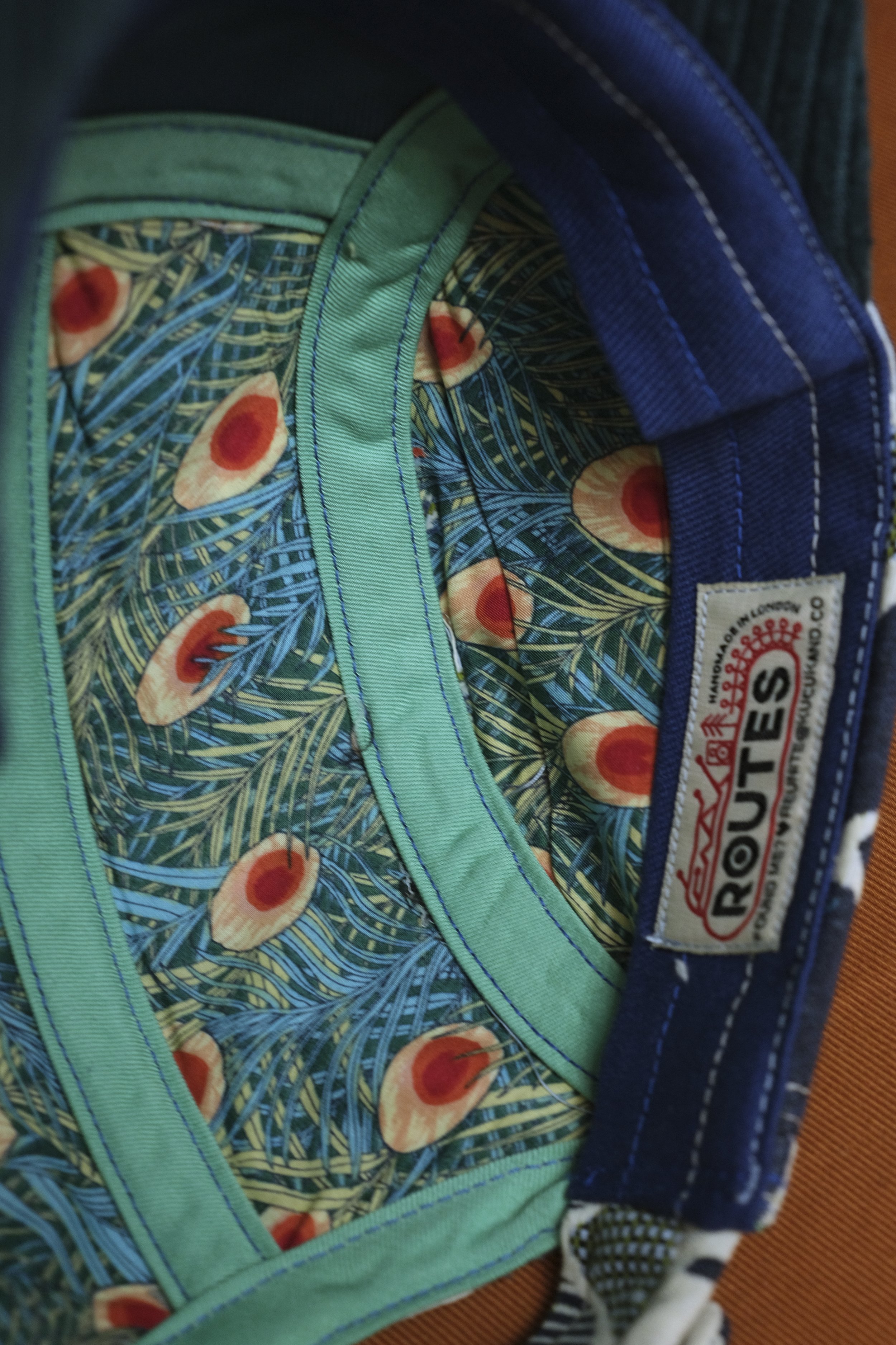 A colorful backpack with a peacock feather and eye pattern lining, blue and green fabric, and a label that reads "ROUTE 66".