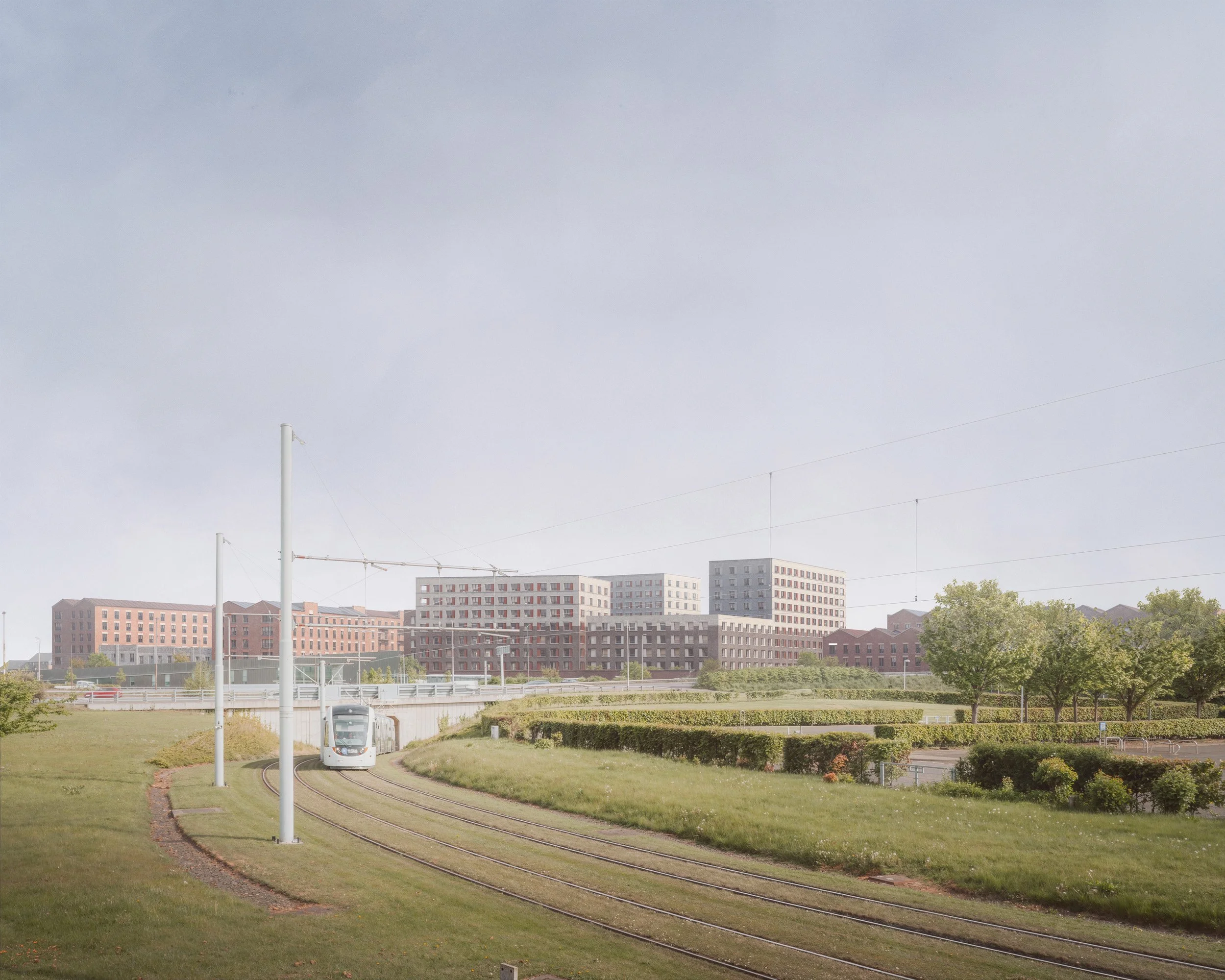 Edinburgh Gateway — wide urban masterplan visualisation showing brick residential buildings, tram infrastructure and landscaped public realm beneath soft atmospheric daylight.