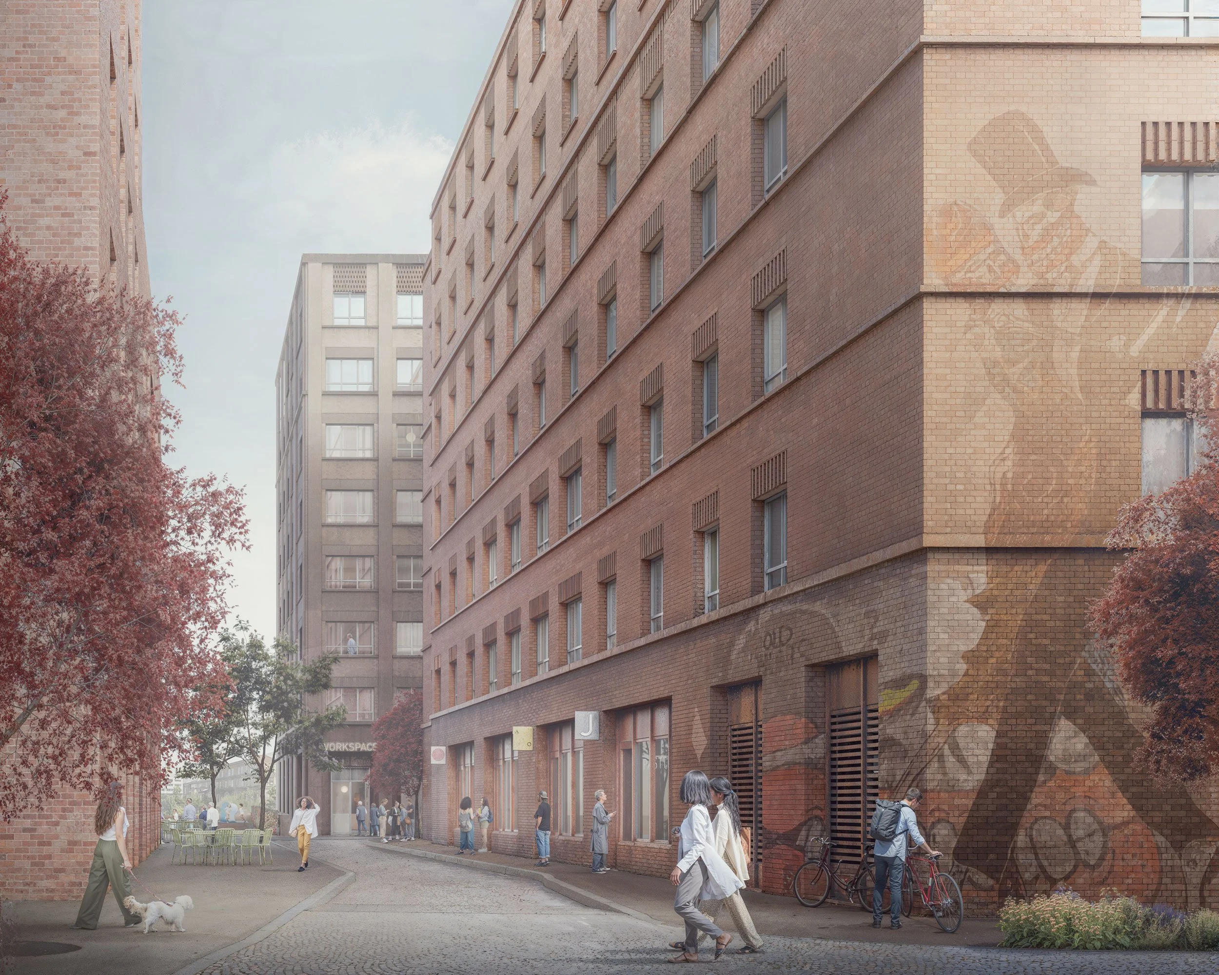People walking and socializing on a city street between brick and concrete buildings with trees and outdoor seating.