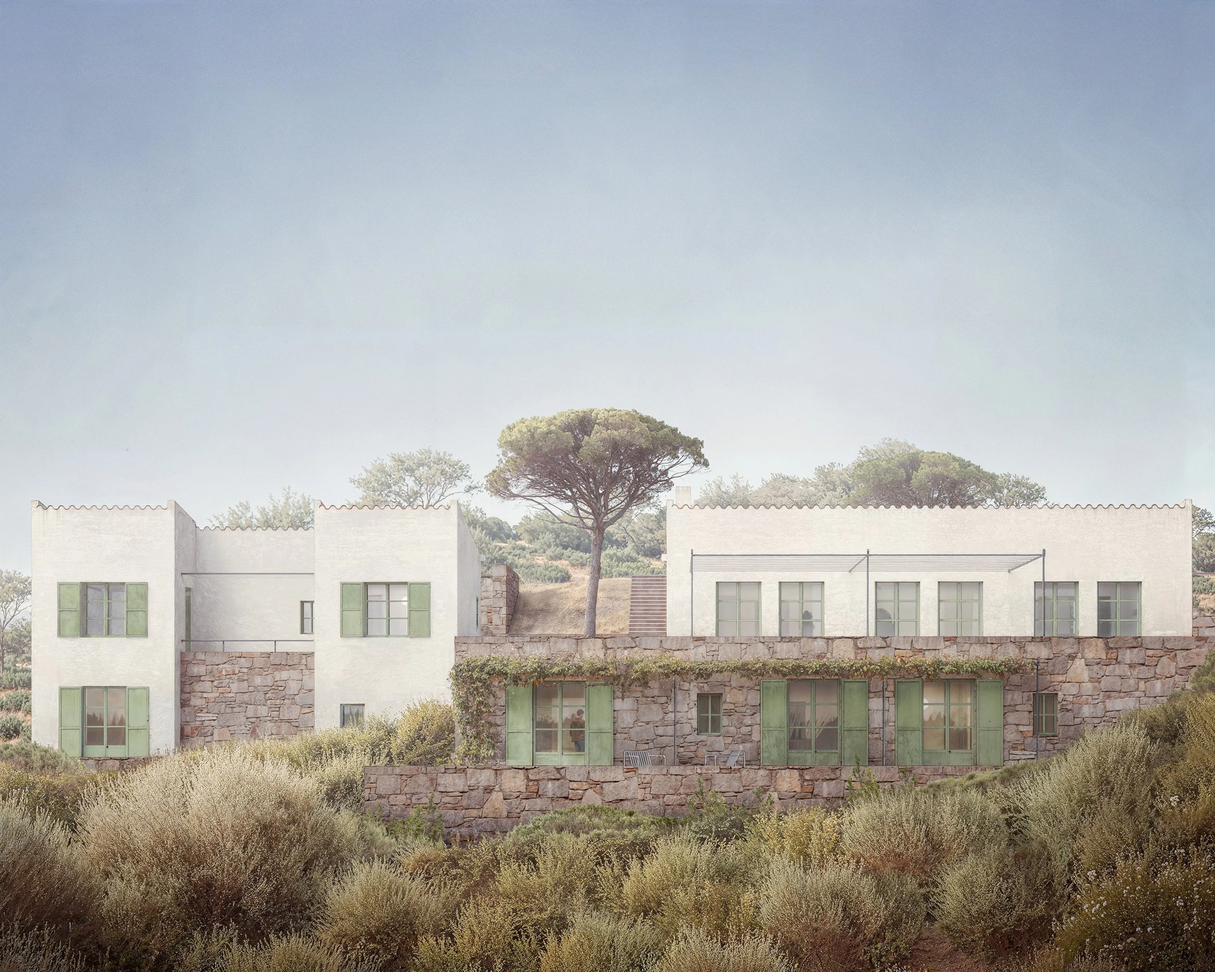 Skiathos — architectural visualisation of a Mediterranean hillside residence with white rendered volumes, stone walls, green shutters and soft coastal landscape planting.