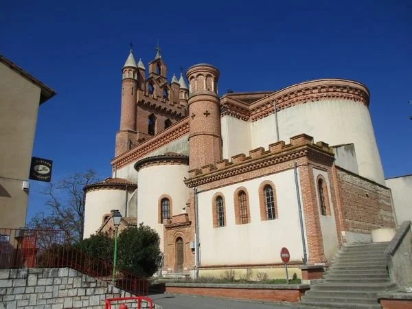 Une ancienne forteresse ou château avec des tours en pierre, situé dans une ville sous un ciel bleu clair.