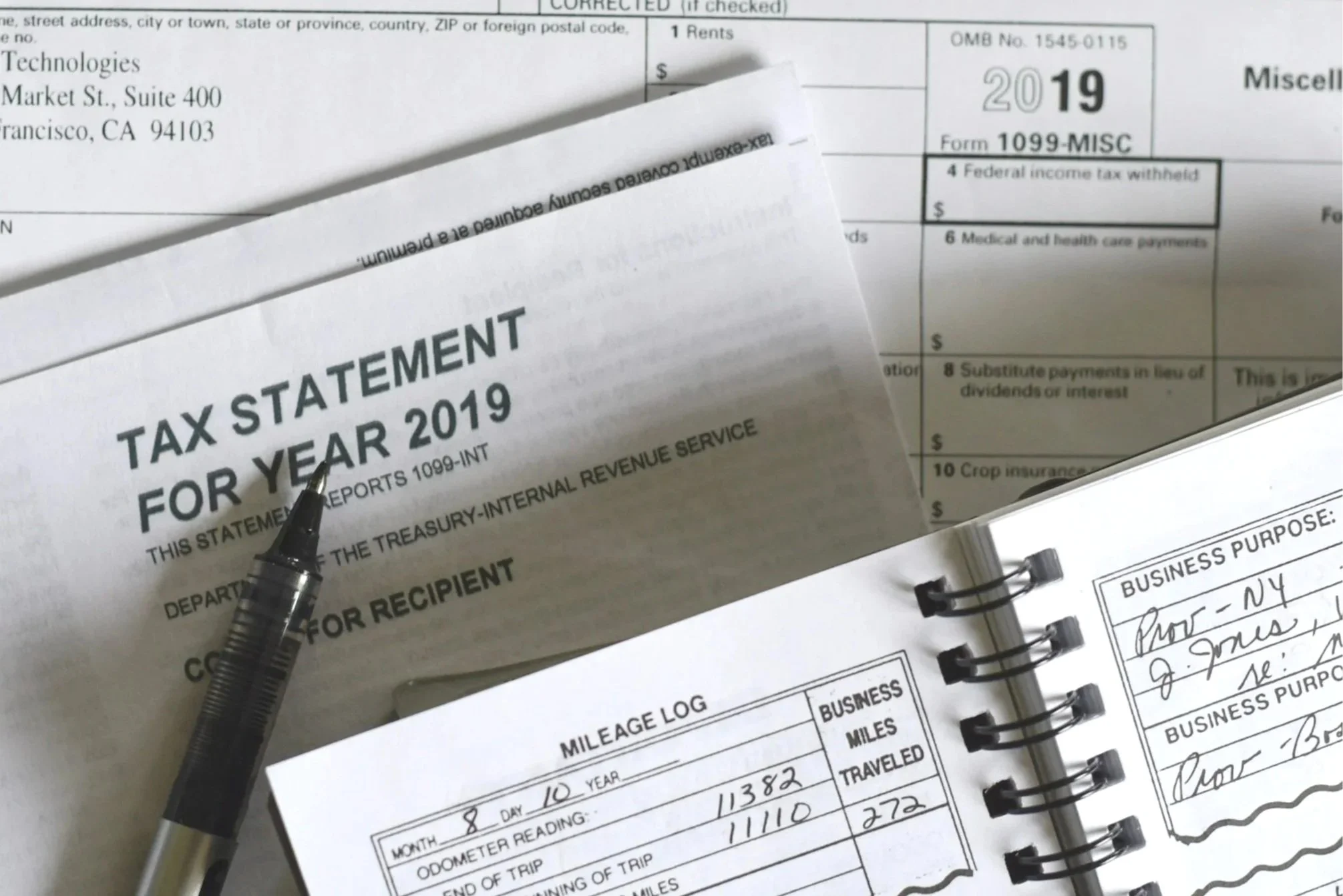 Close-up of tax documents, including a tax statement for 2019, with handwritten notes and a black pen resting on the papers.